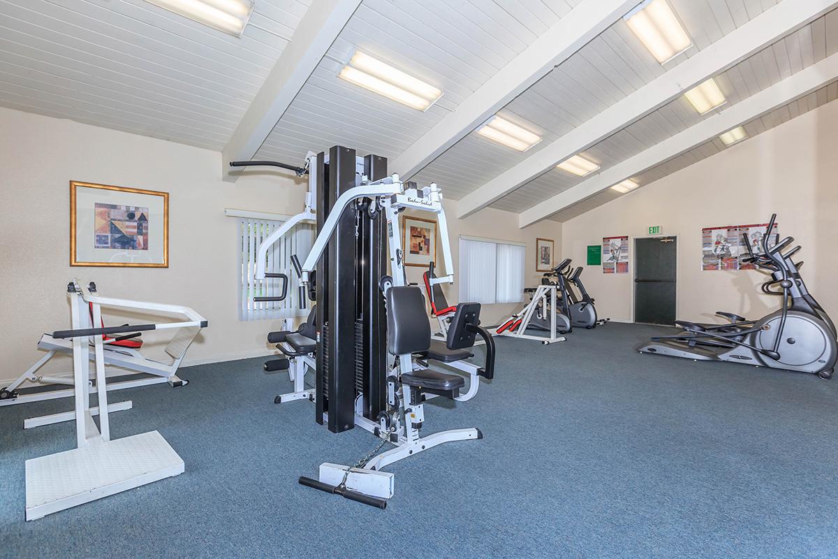 Empty gym space featuring a variety of exercise equipment, including strength training machines, an elliptical machine, and a stationary bike. 