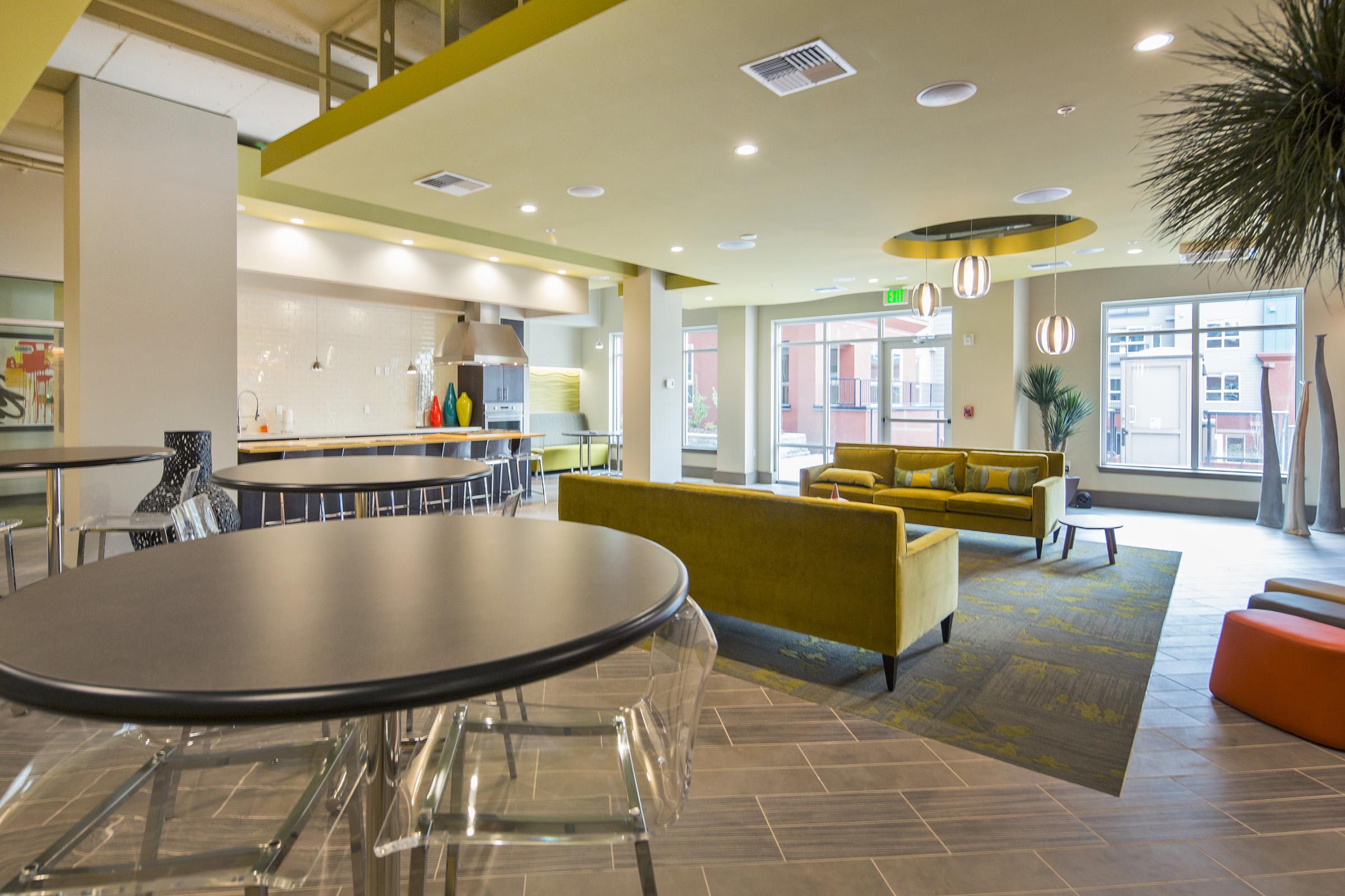 Modern common area with stylish furnishings, including a bright yellow sofa and colorful decor.