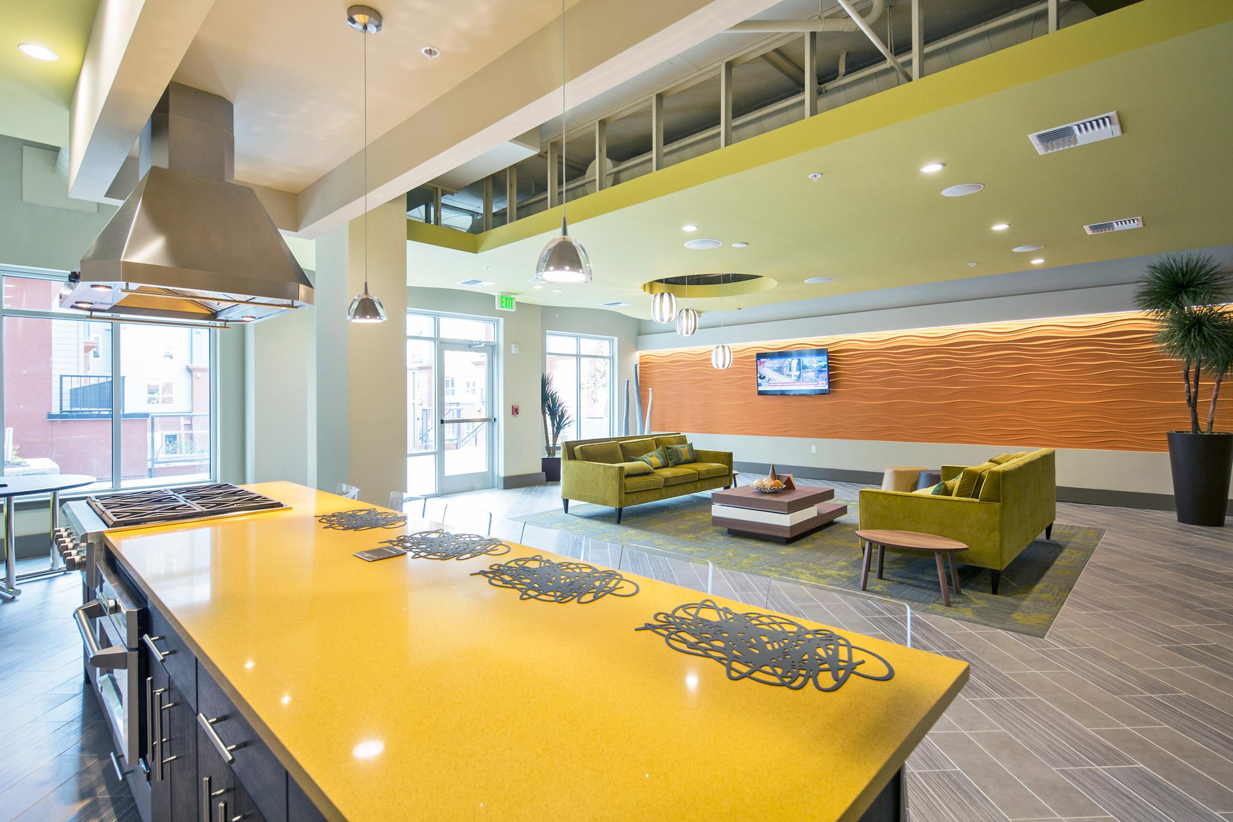 A modern lounge area featuring a sleek kitchen island with a yellow countertop, stylish black cabinets, and decorative placemats.
