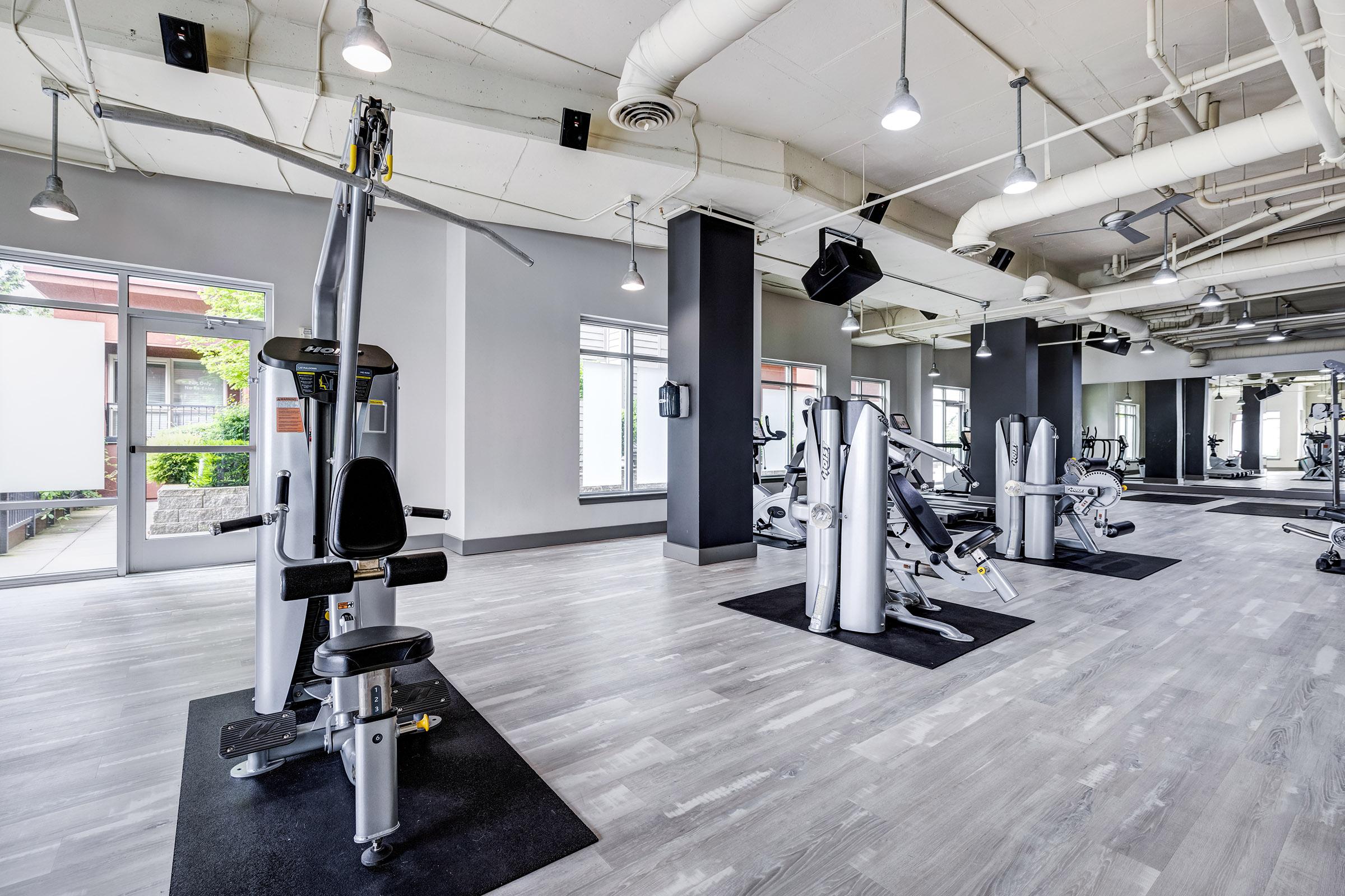 : A modern gym interior featuring various workout machines including strength training equipment.