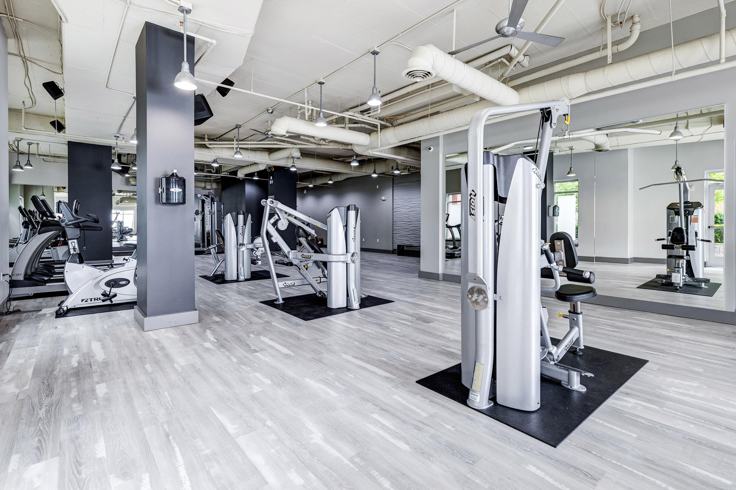 A spacious gym area featuring various exercise machines and equipment, including weight machines and cardio machines.