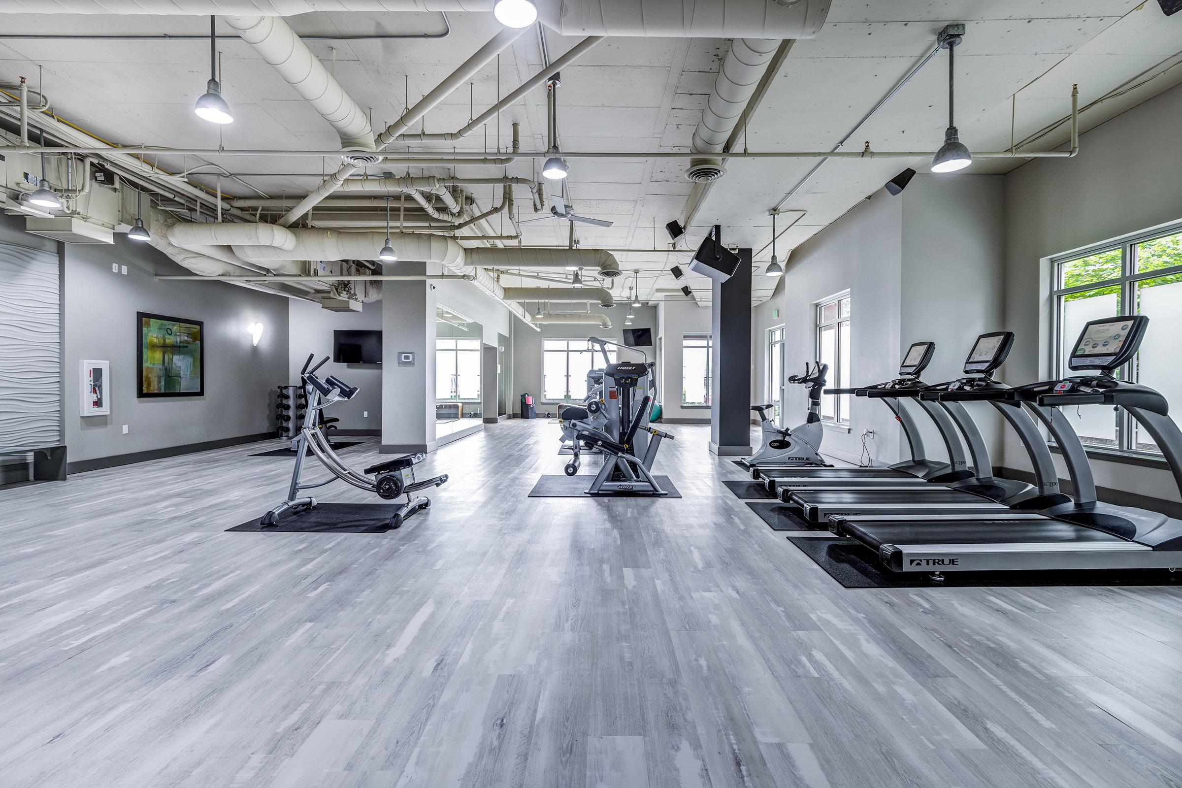 A modern gym interior featuring several exercise machines, including treadmills and a stationary bike.