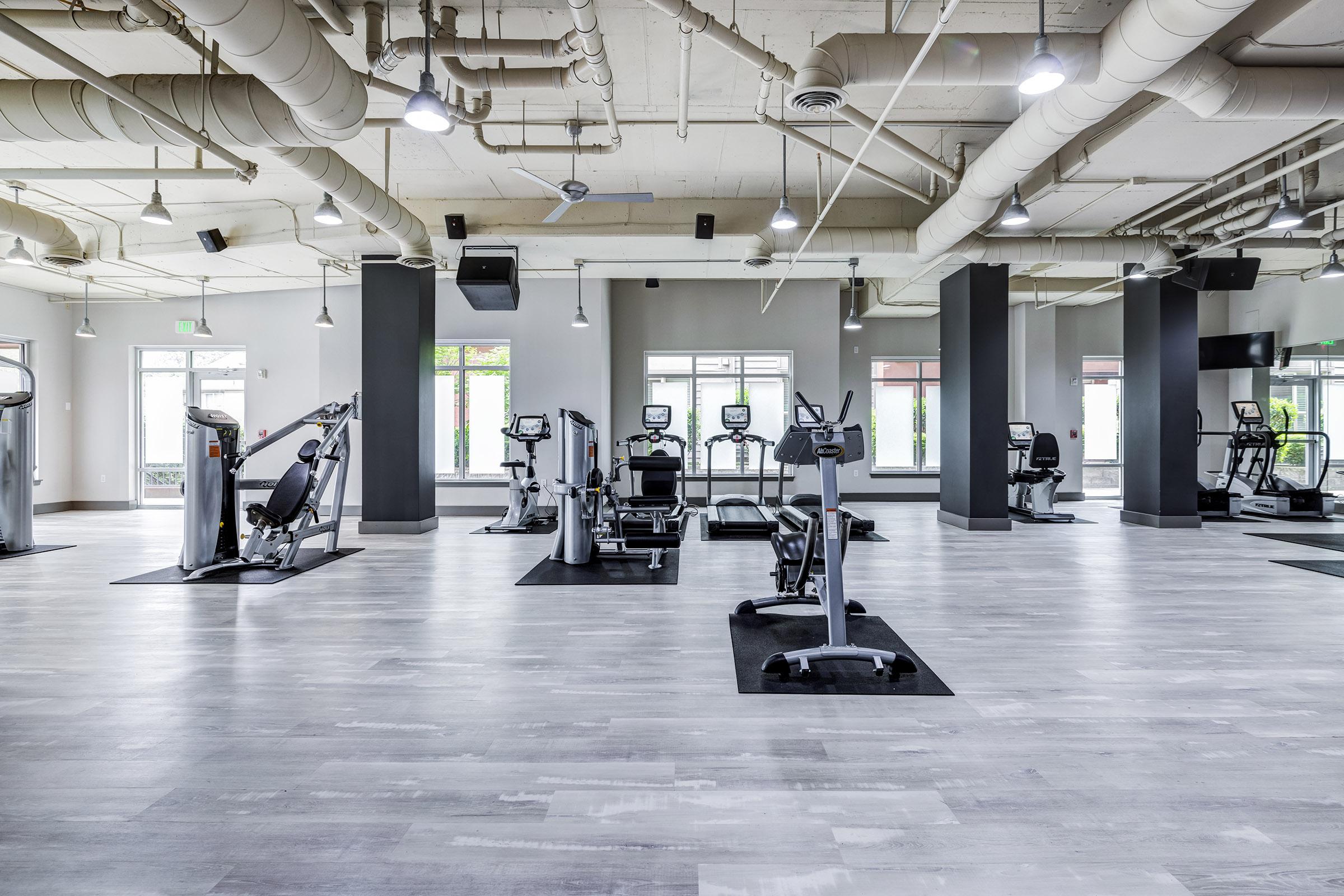 A spacious modern gym with various exercise equipment, including treadmills, stationary bikes, and weight machines.