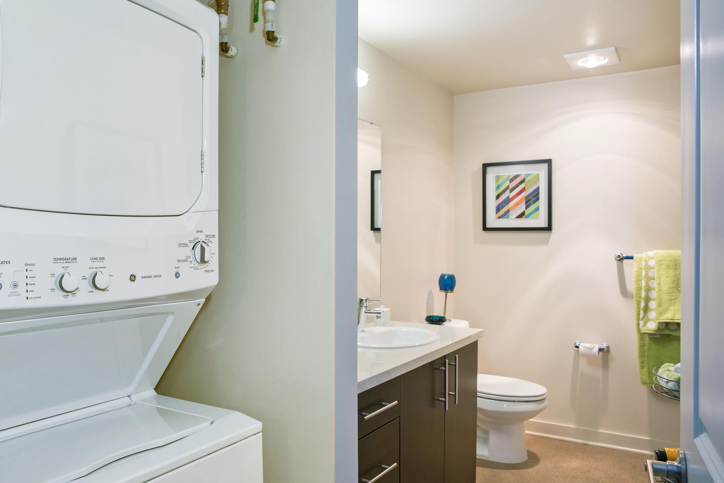 A modern laundry area featuring a stacked washer and dryer on the left.