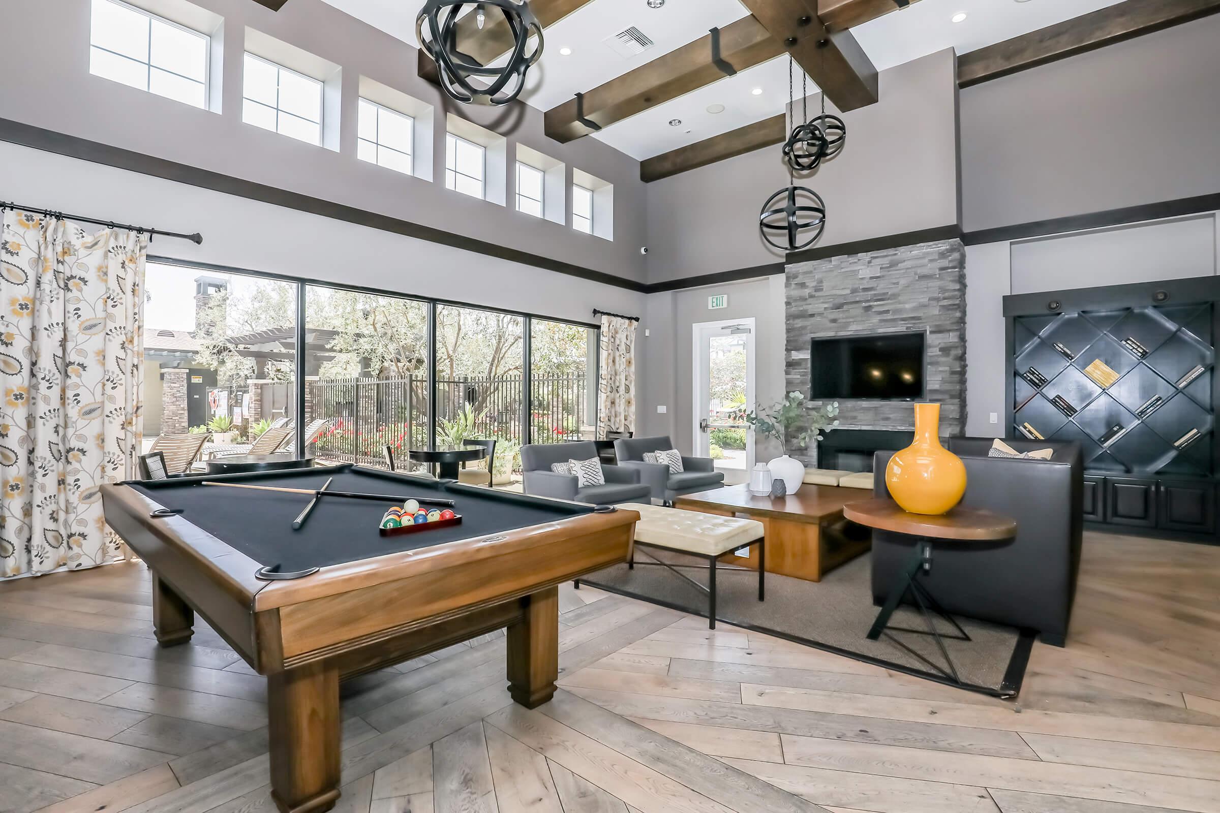 Apartments in Oxnard, CA with In-Unit Washer and Dryer - Artisan at East Village - Clubhouse with a Billiards Table, Couches, and a Bookcase