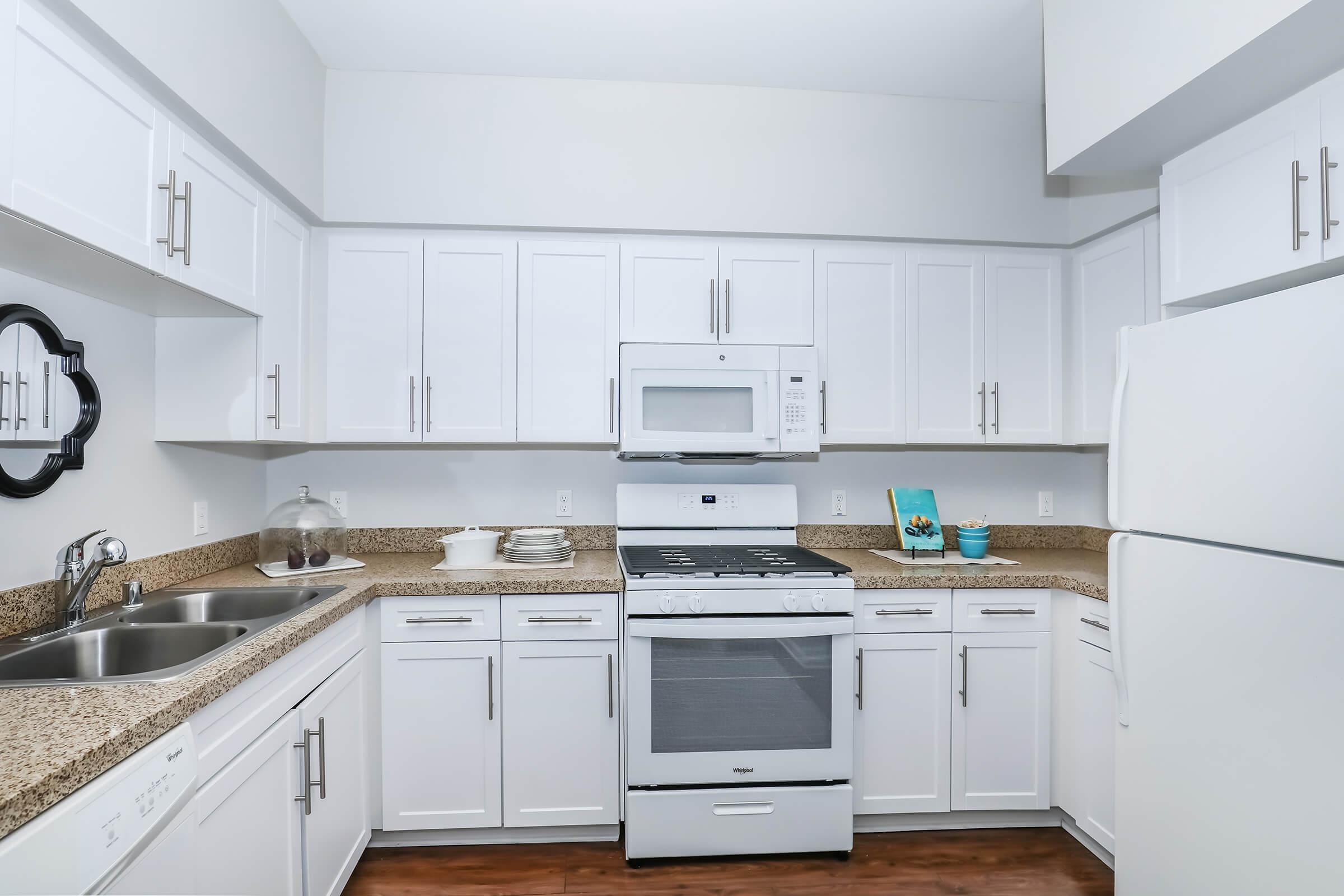 Apartments Near Mandalay Bay in Oxnard, CA - Artisan at East Village - Kitchen Completed with Appliances, Modern White Cabinets, and Chrome Finishes