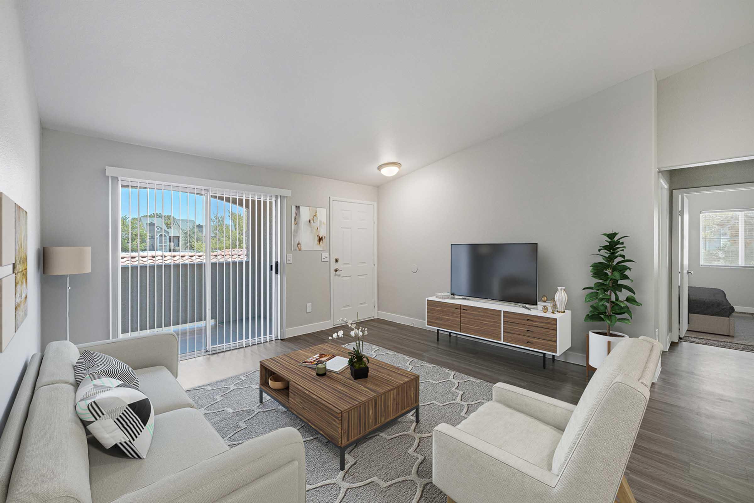 A modern living room featuring a light-colored sofa and armchair, a wooden coffee table, and a flat-screen TV on a console. Large sliding glass doors with curtains provide natural light, and a potted plant adds a touch of greenery. The walls are painted in neutral tones, creating a bright and inviting atmosphere.