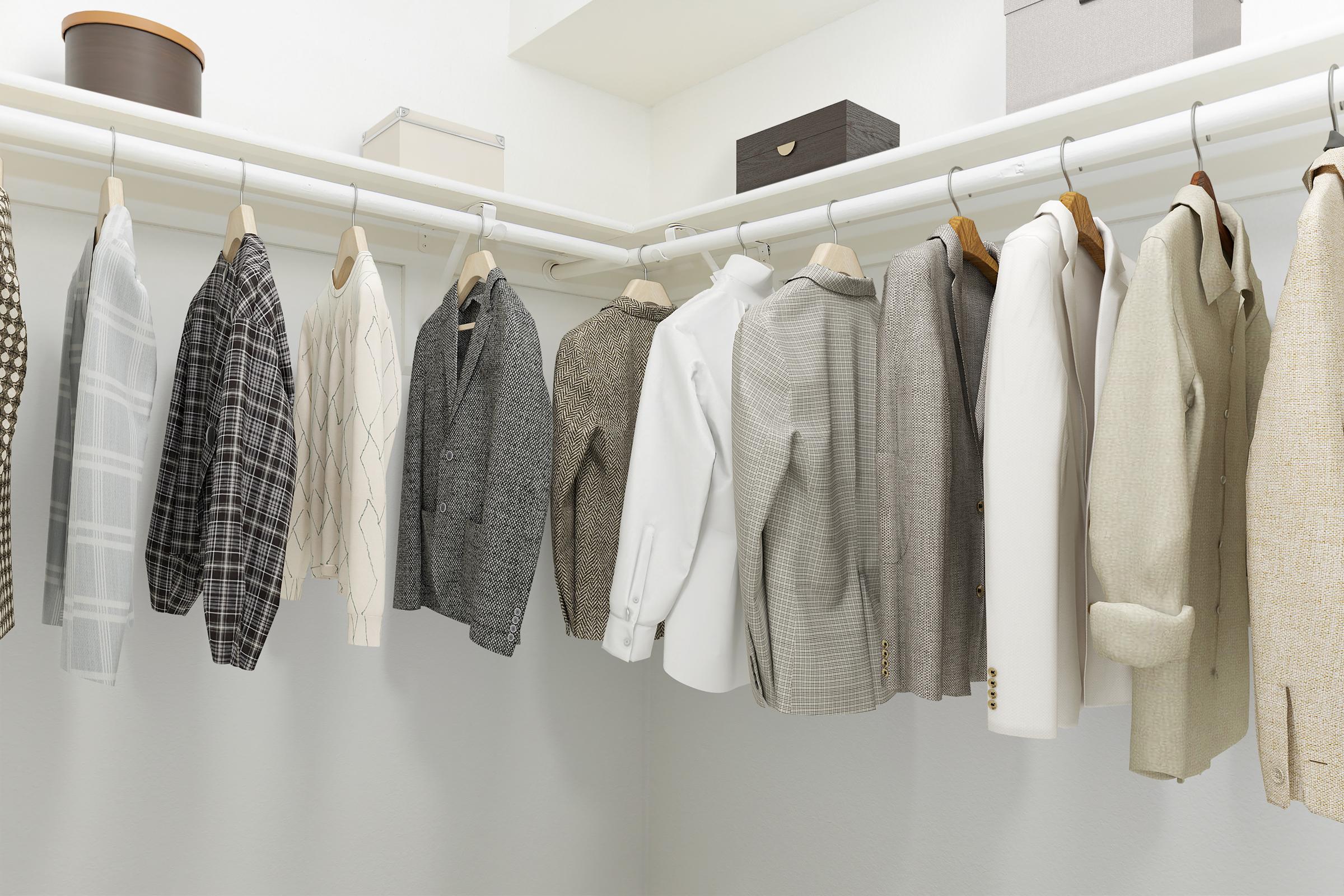 A well-organized closet featuring a variety of jackets and blazers in different colors and patterns, including plaid and textured fabrics. The garments are neatly hung on white hangers, and there are storage boxes on the upper shelves, contributing to a tidy and stylish appearance.