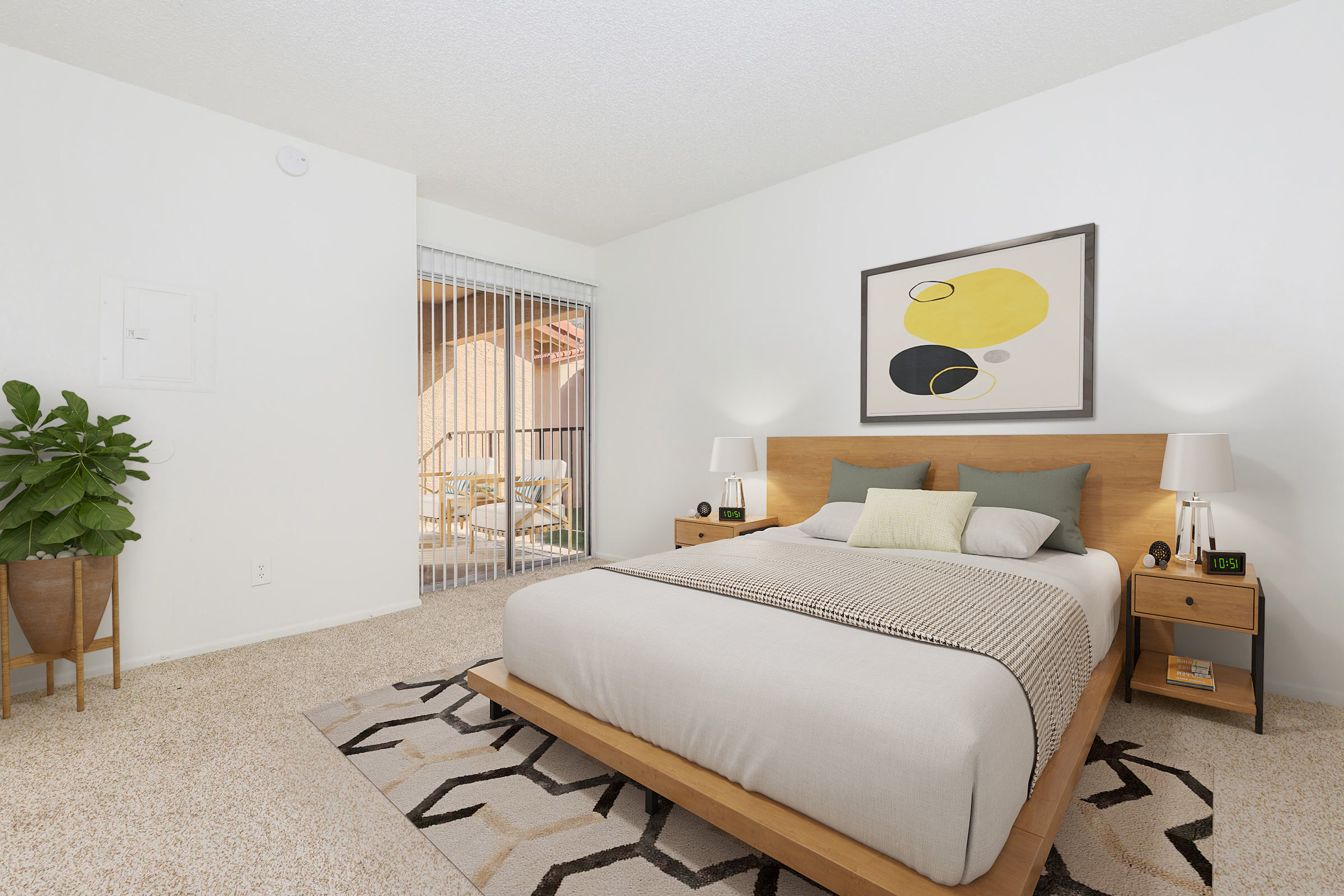 A cozy bedroom featuring a wooden bed with light bedding, bedside tables with lamps, and a geometric rug. A large window with sliding glass doors leads to an outdoor space, and a potted plant adds a touch of greenery to the room. The walls are painted white, creating a bright, airy atmosphere.