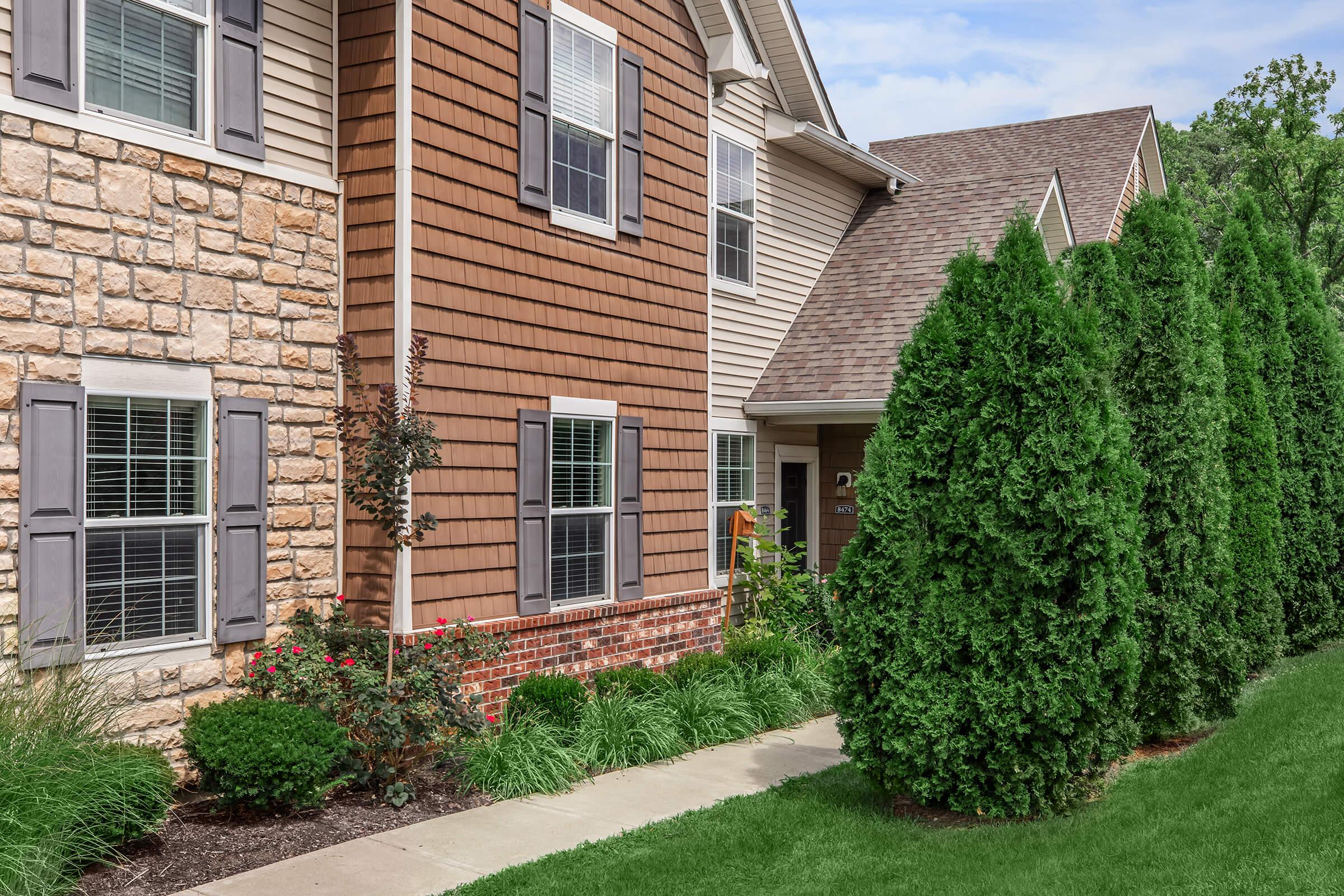 a house with bushes in front of a brick building