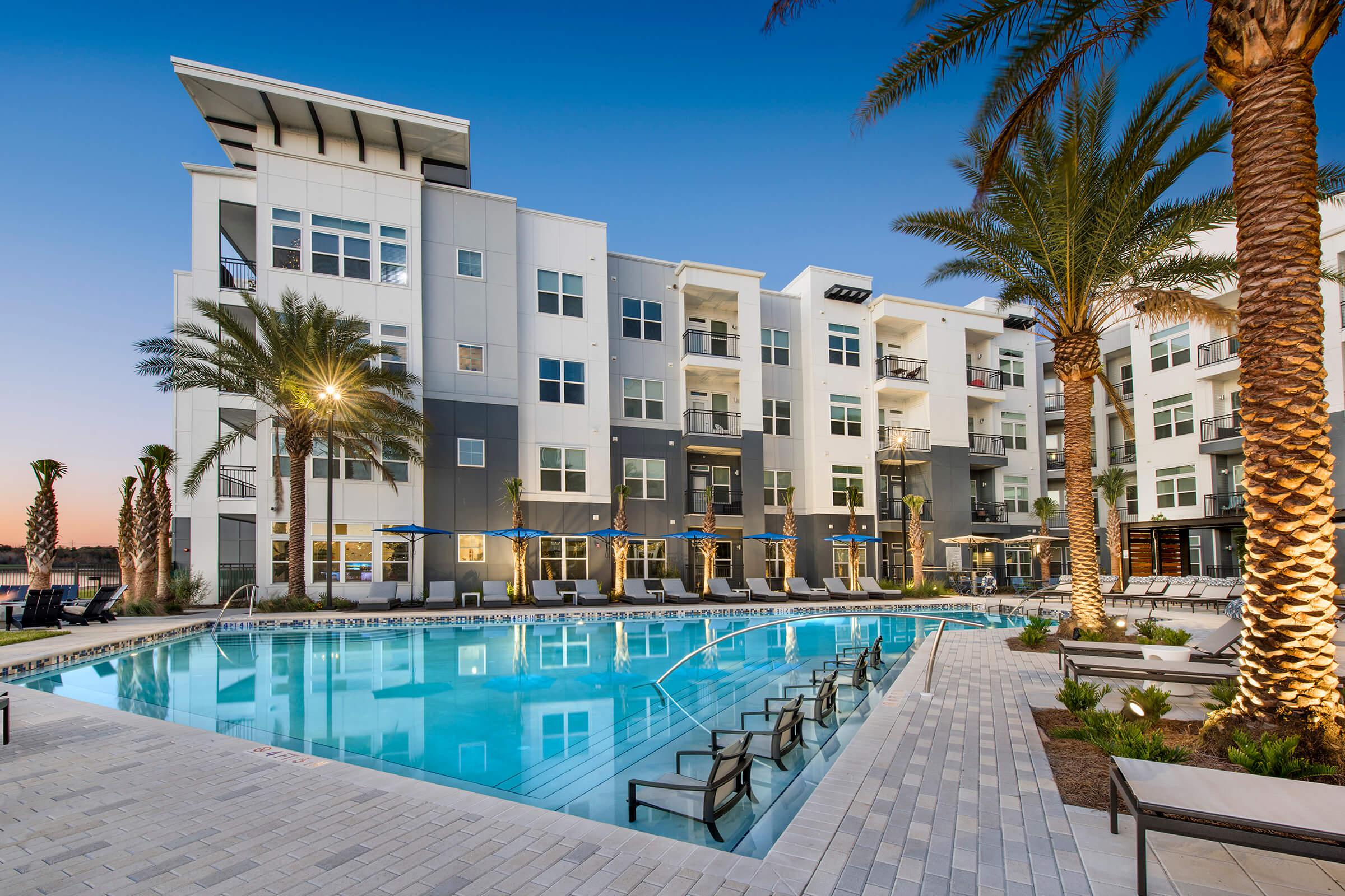 a pool next to a palm tree in front of a building