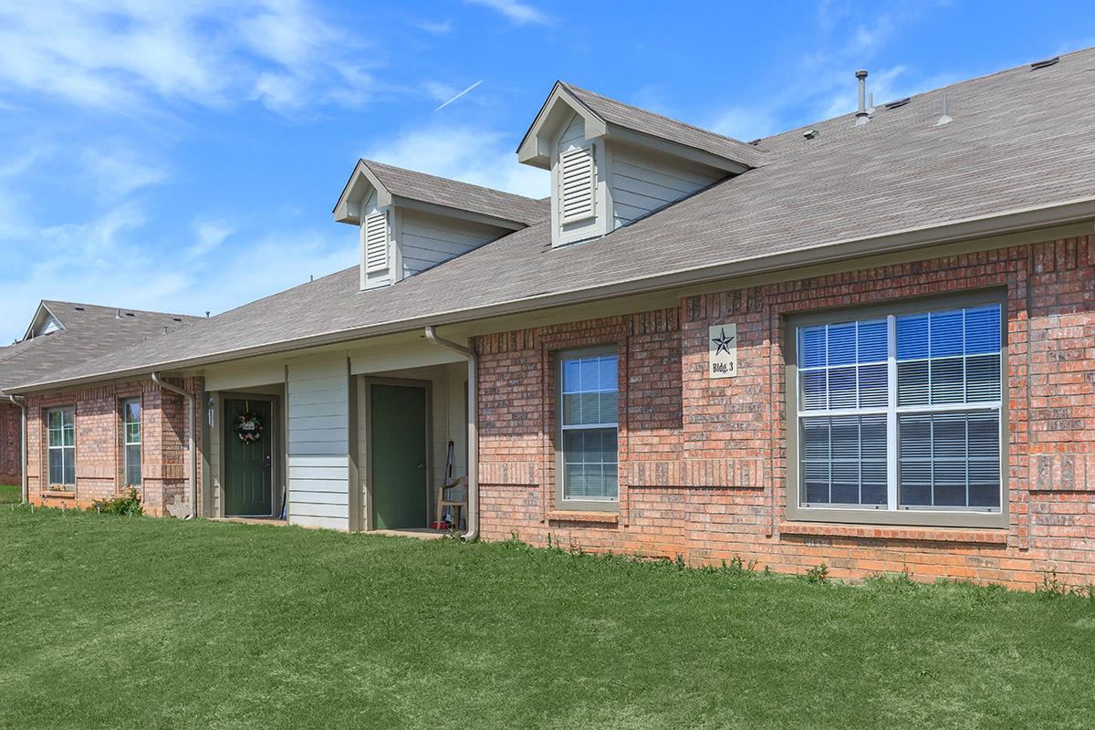 a large brick building with grass in front of a house