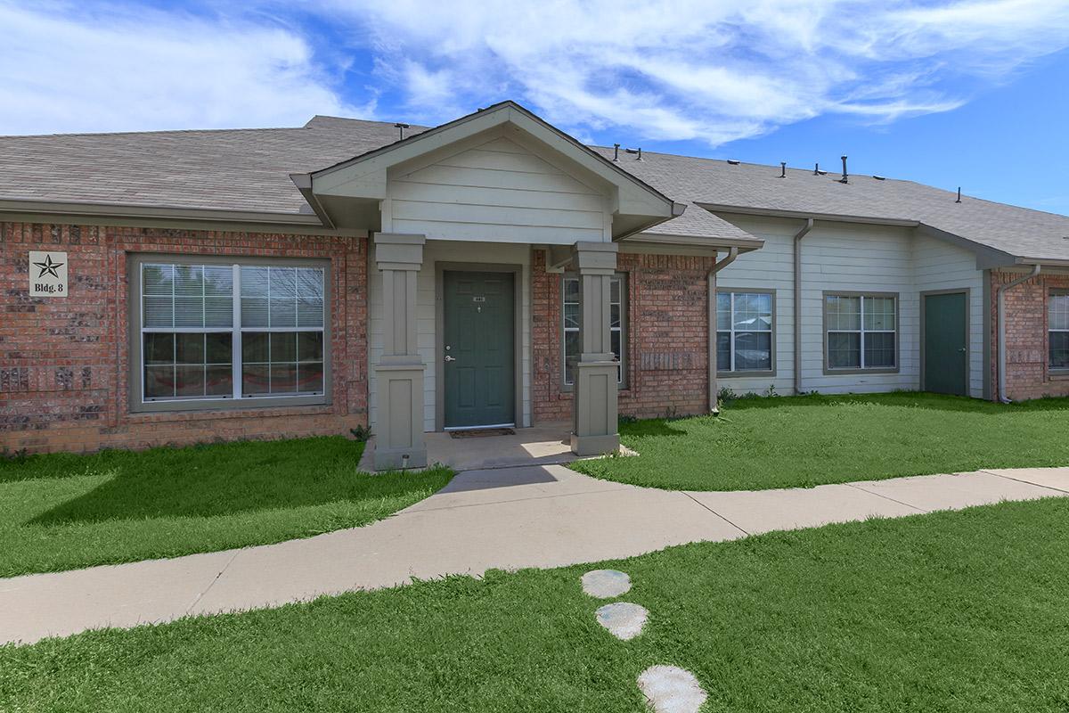 a house with a lawn in front of a brick building