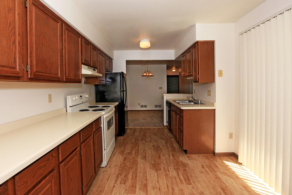 a kitchen with wooden cabinets and a wood floor