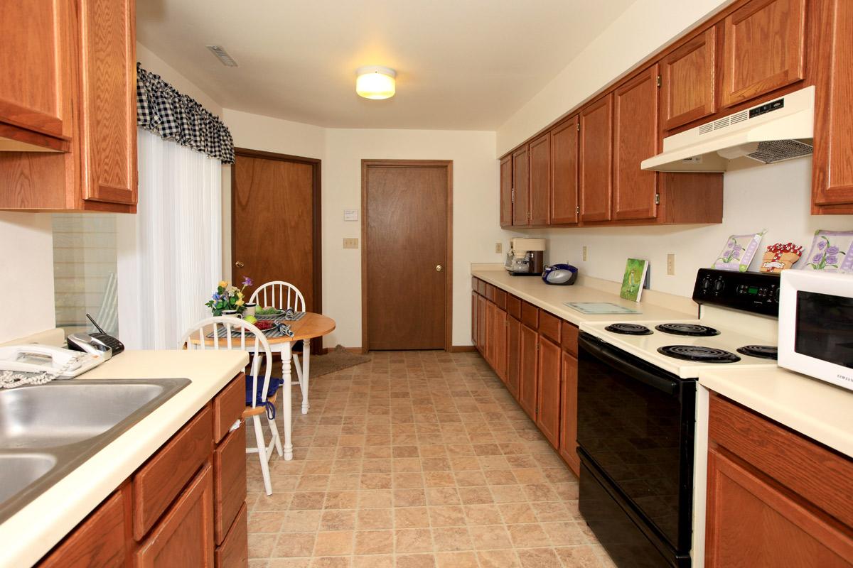 a kitchen with a stove a sink and a microwave oven above a refrigerator