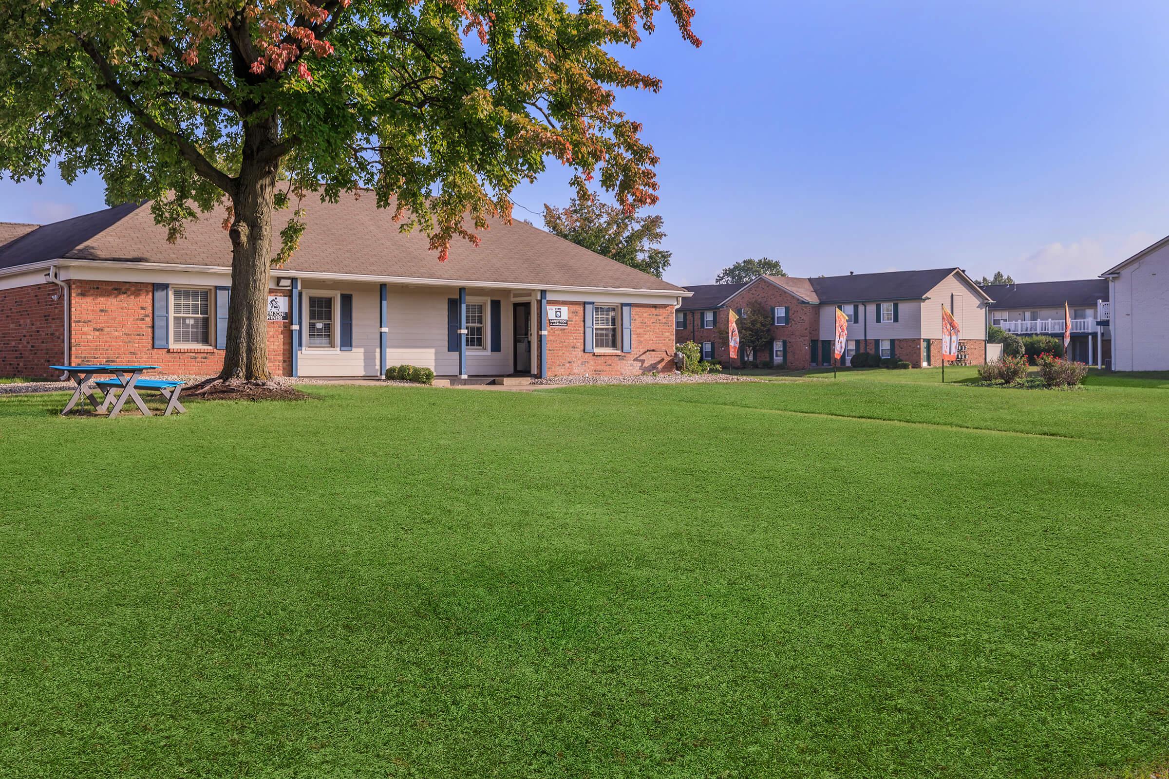 a large brick building with green grass in front of a house