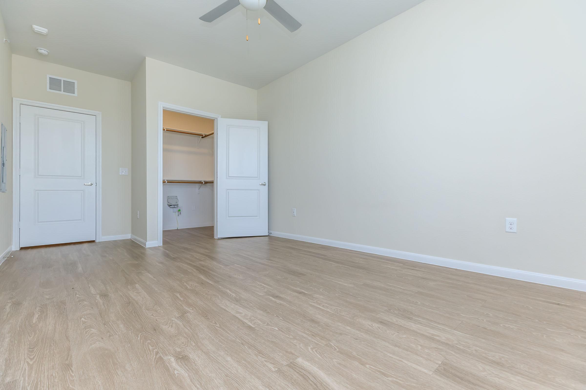 Two Bedroom Senior Apartments in Pflugerville TX - Legacy Ranch at Dessau East - Spacious Bedroom with Sleek Wood-Style Flooring, Large Closet, and a Ceiling Fan