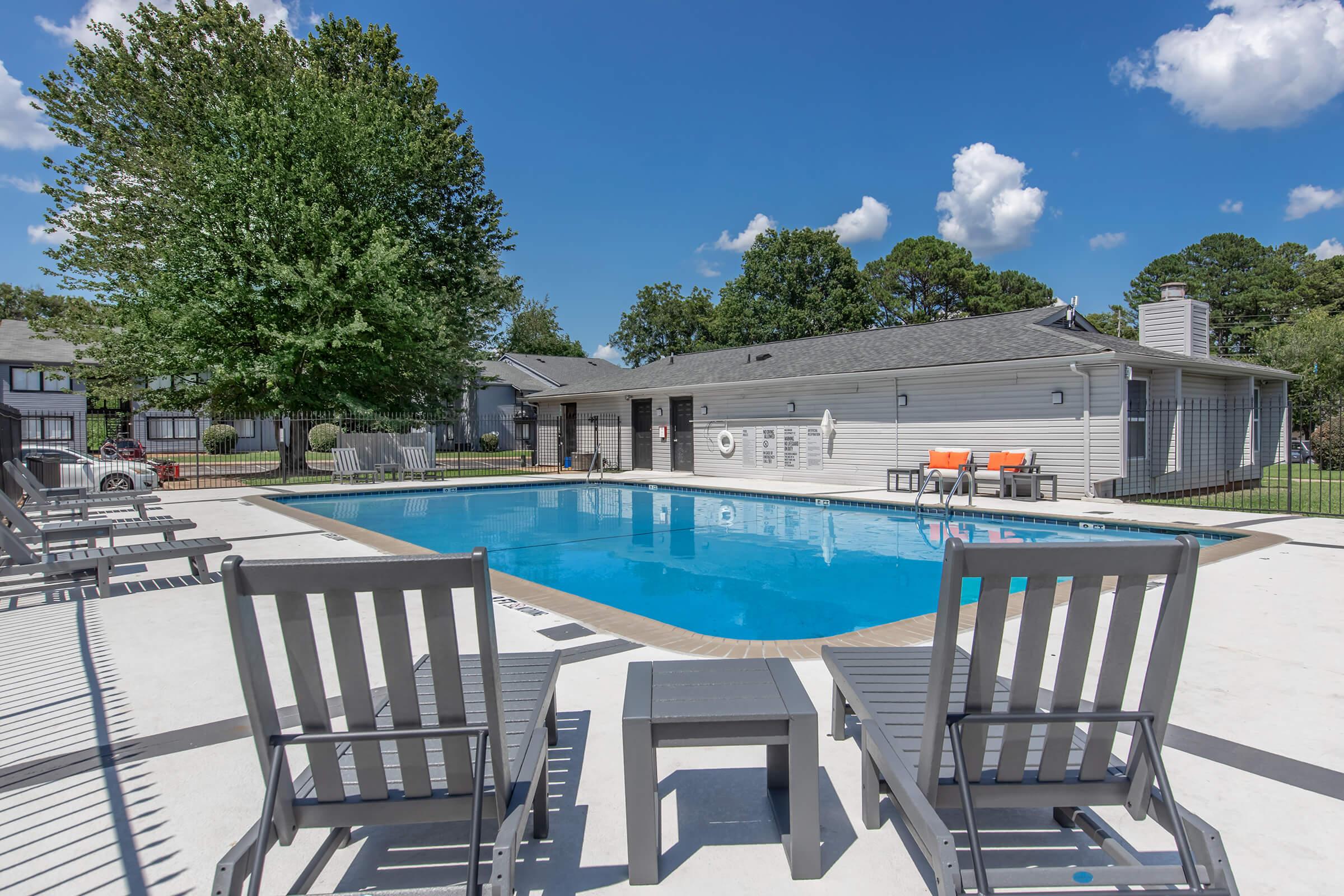 a row of lawn chairs sitting on a bench next to a pool