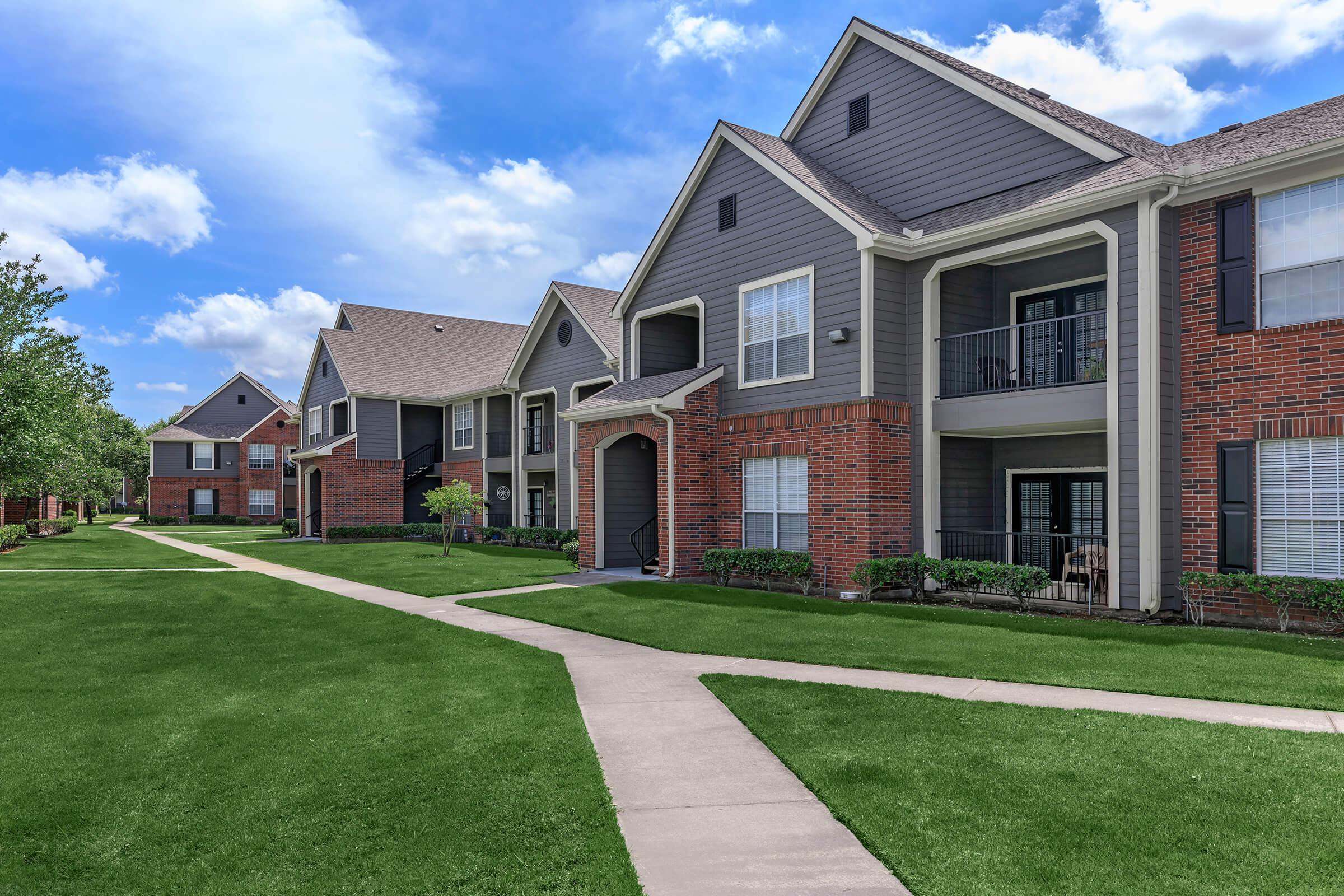 a large brick building with grass in front of a house