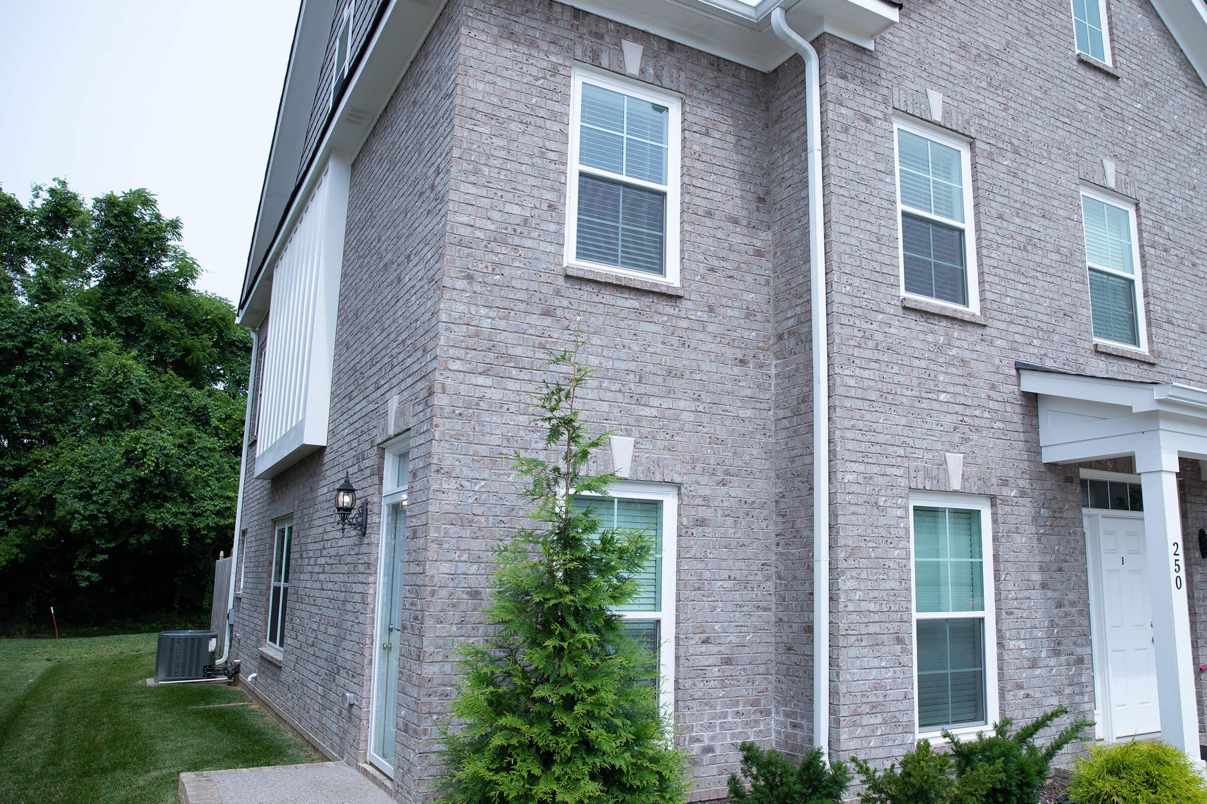 a house with bushes in front of a brick building