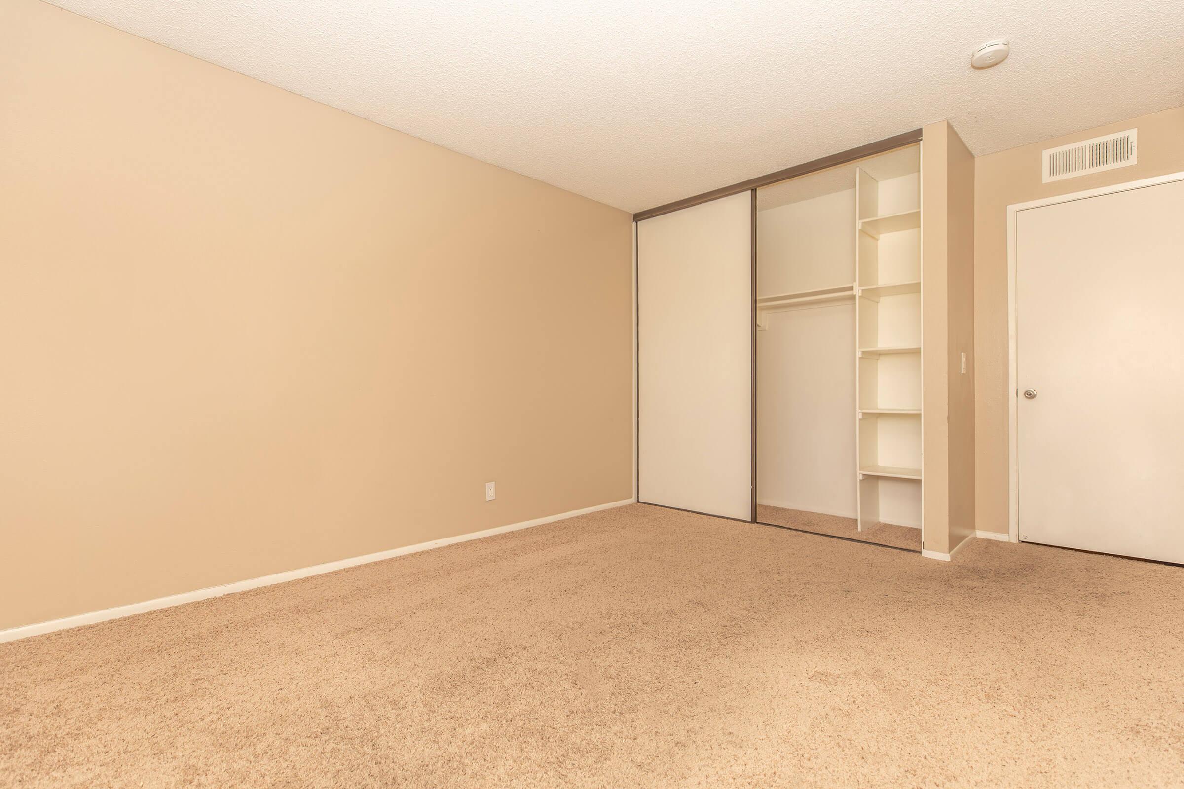 carpeted bedroom with open closet with shelves
