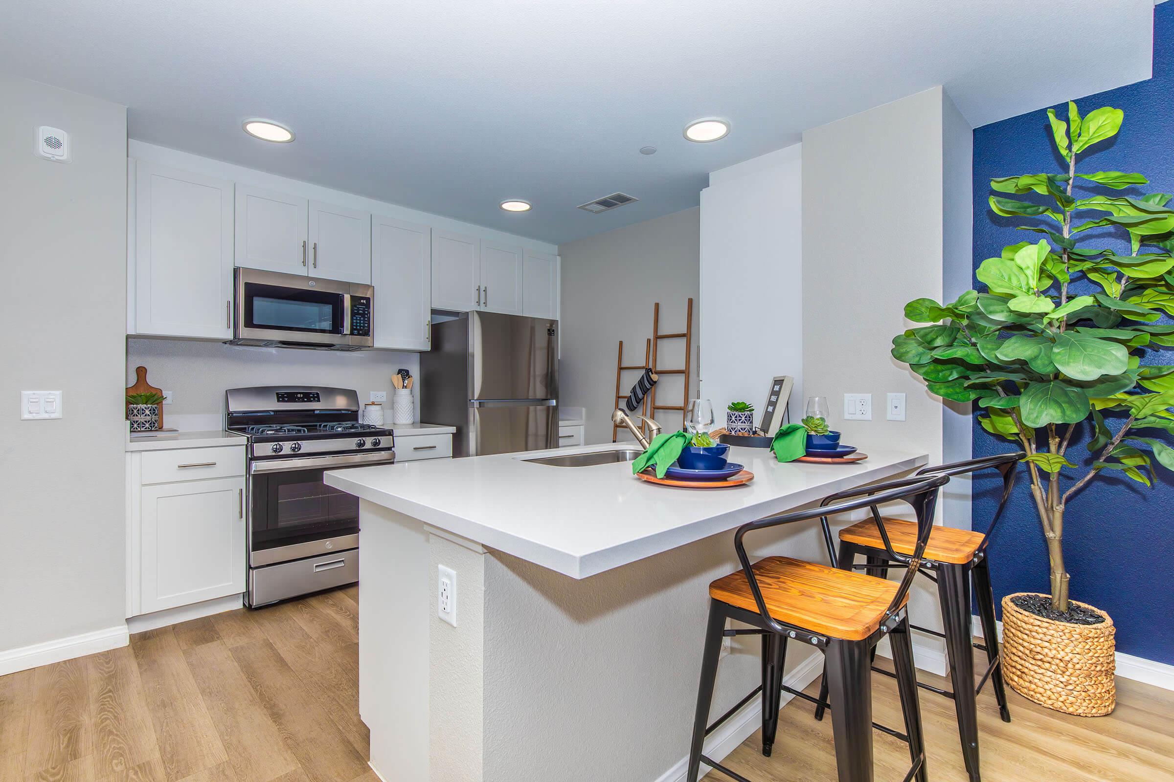 Apartments Near Preisker Park in Santa Maria, CA - Azure Apartments - Kitchen with Stainless Steel Appliances, a Breakfast Bar, and white cabinets.