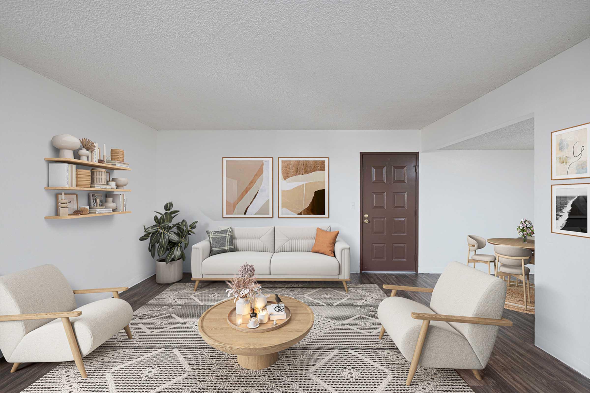 A modern living room featuring a light-colored sofa with decorative pillows, two stylish armchairs, a round coffee table with a centerpiece, and a patterned area rug. Walls are adorned with abstract artwork, and a shelf holds decorative items. A doorway leads to another room, and a dining area is visible in the background.
