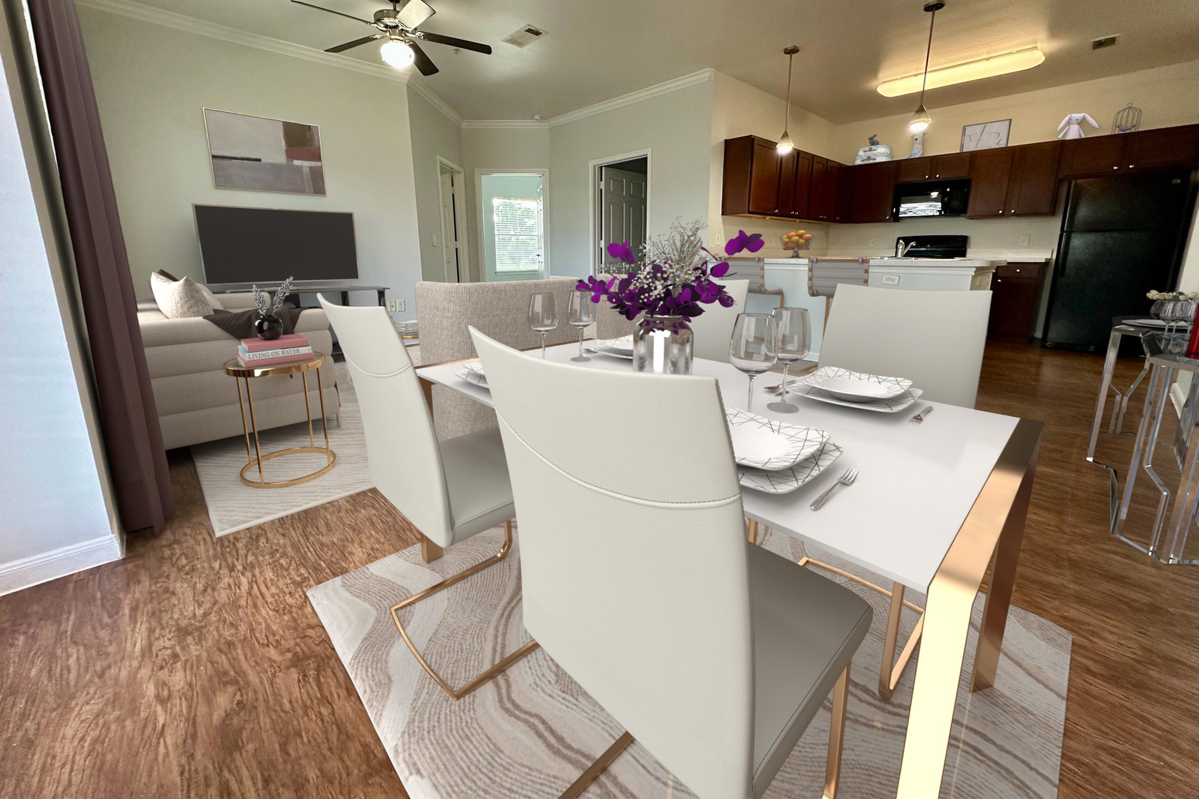 A modern dining area featuring a white table set with plates and glasses, surrounded by stylish chairs. In the background, a cozy living space with a sofa and large window, and a kitchen with dark wood cabinets and stainless steel appliances visible. Brightly lit with a welcoming ambiance.