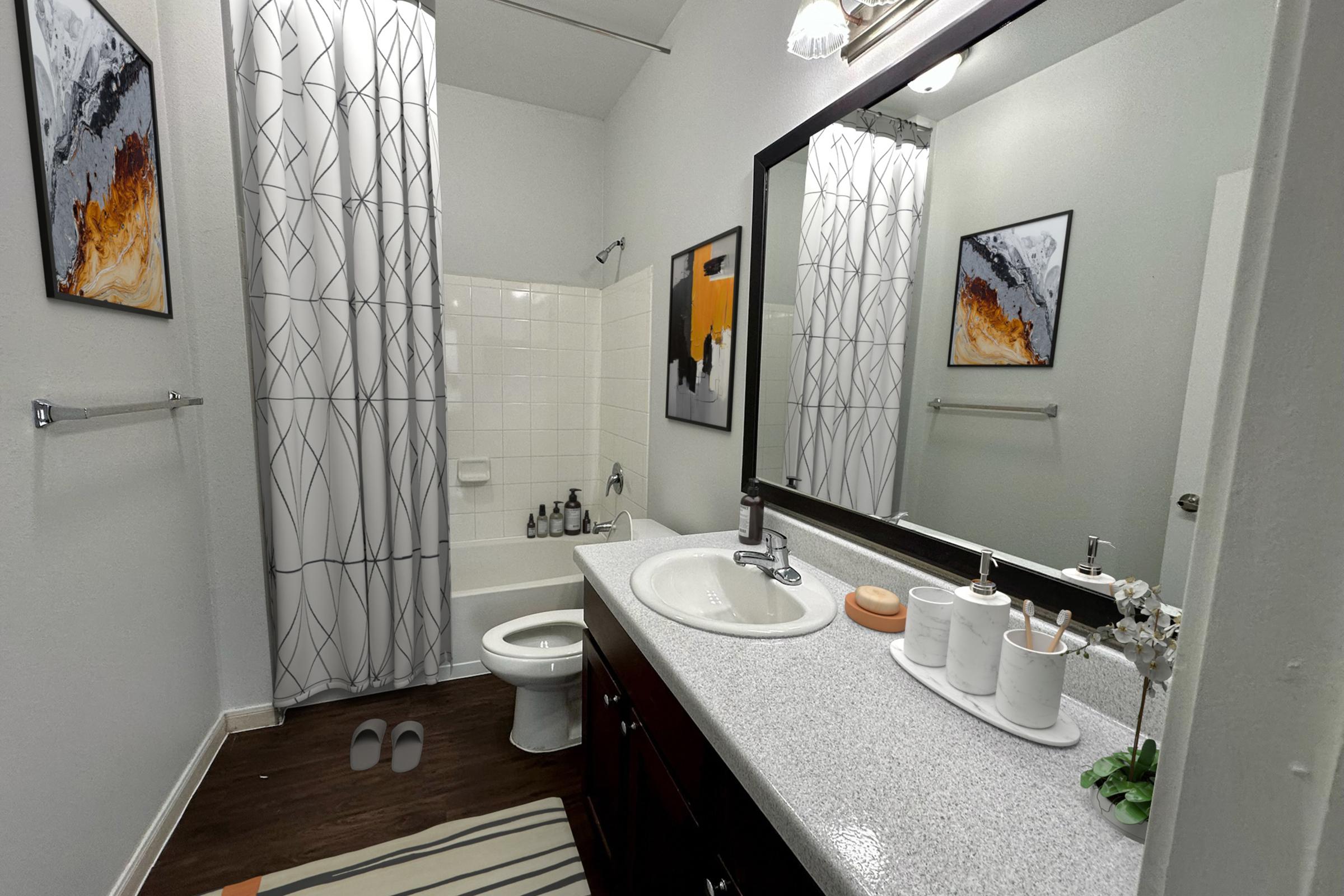 A modern bathroom featuring a bathtub with a white shower curtain, a large mirror above a double sink vanity, and stylish decor including a wall art piece. The flooring is dark wood, and there's a small area rug. Accessories like soap dispensers and a potted plant are present on the counter.
