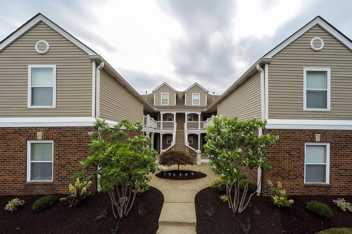 a house with trees in front of a brick building
