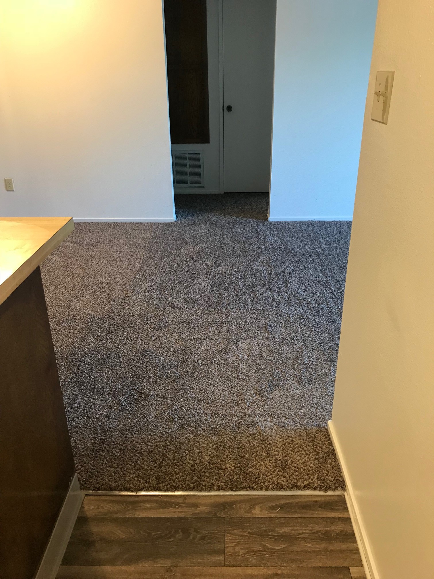 Wooden kitchen flooring and carpeted dining room