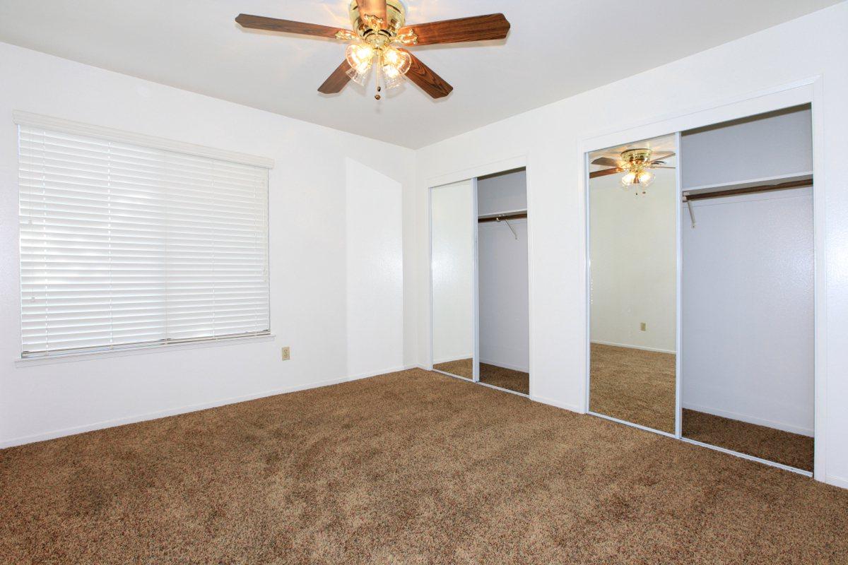 Vacant bedroom with two open sliding mirror glass closet doors