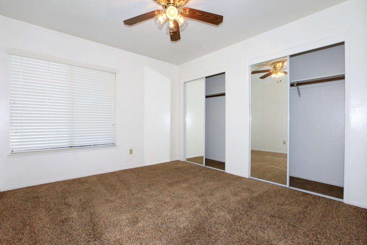 Vacant carpeted bedroom with sliding mirror closet doors