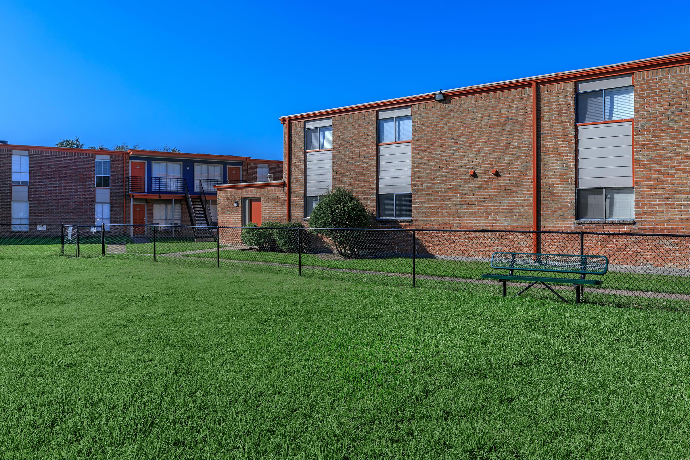 a large brick building with green grass in front of a house