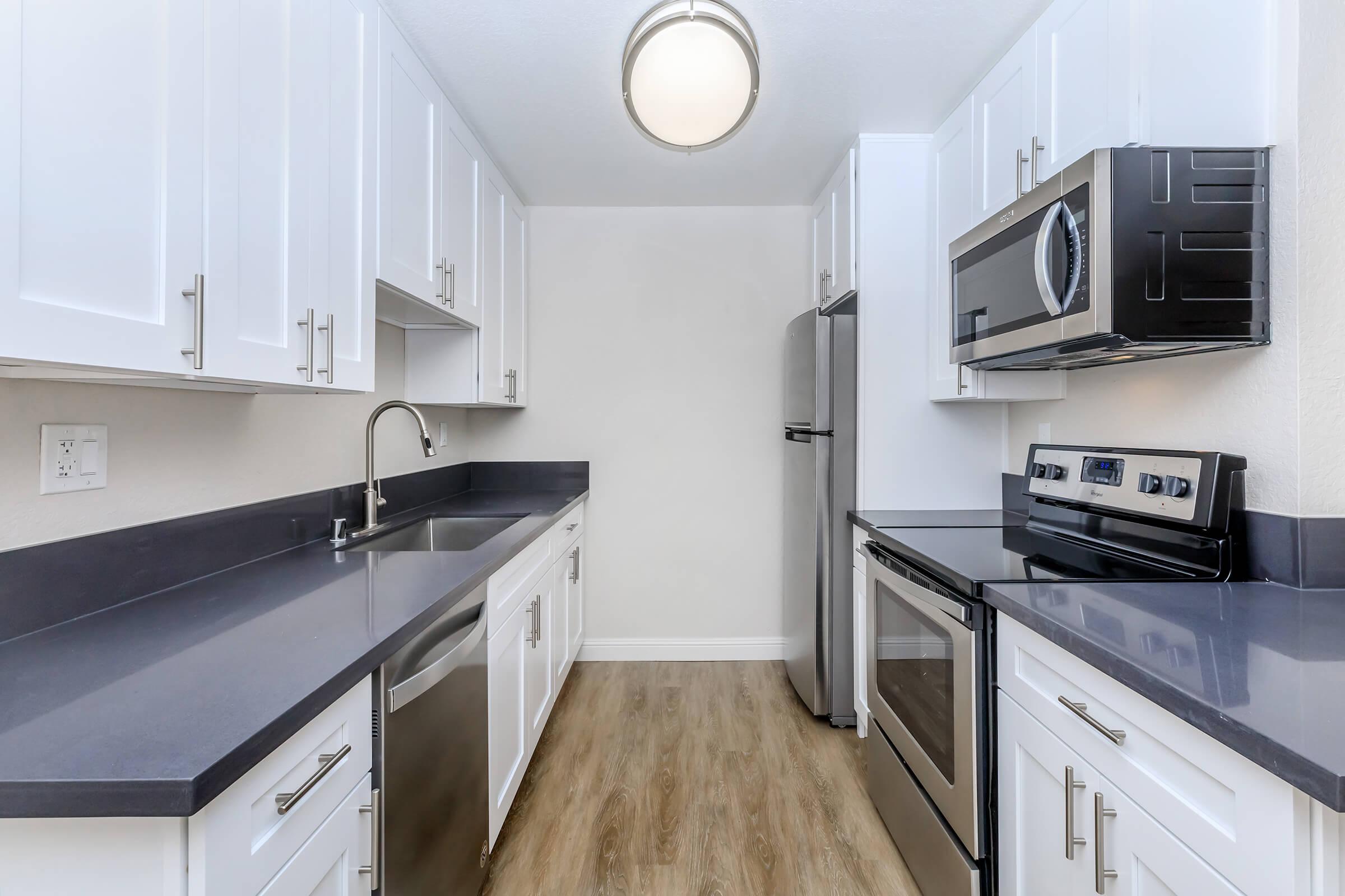 a kitchen with white cabinets and black counter