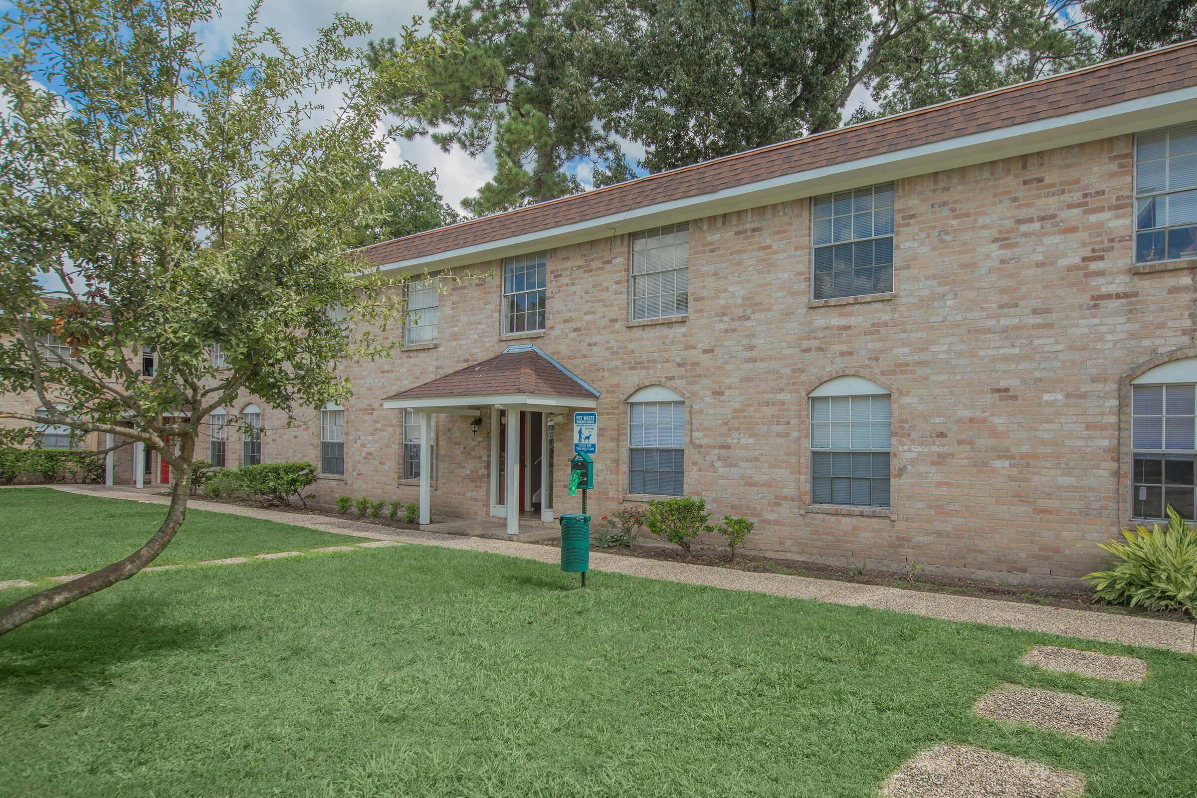a large brick building with grass in front of a house