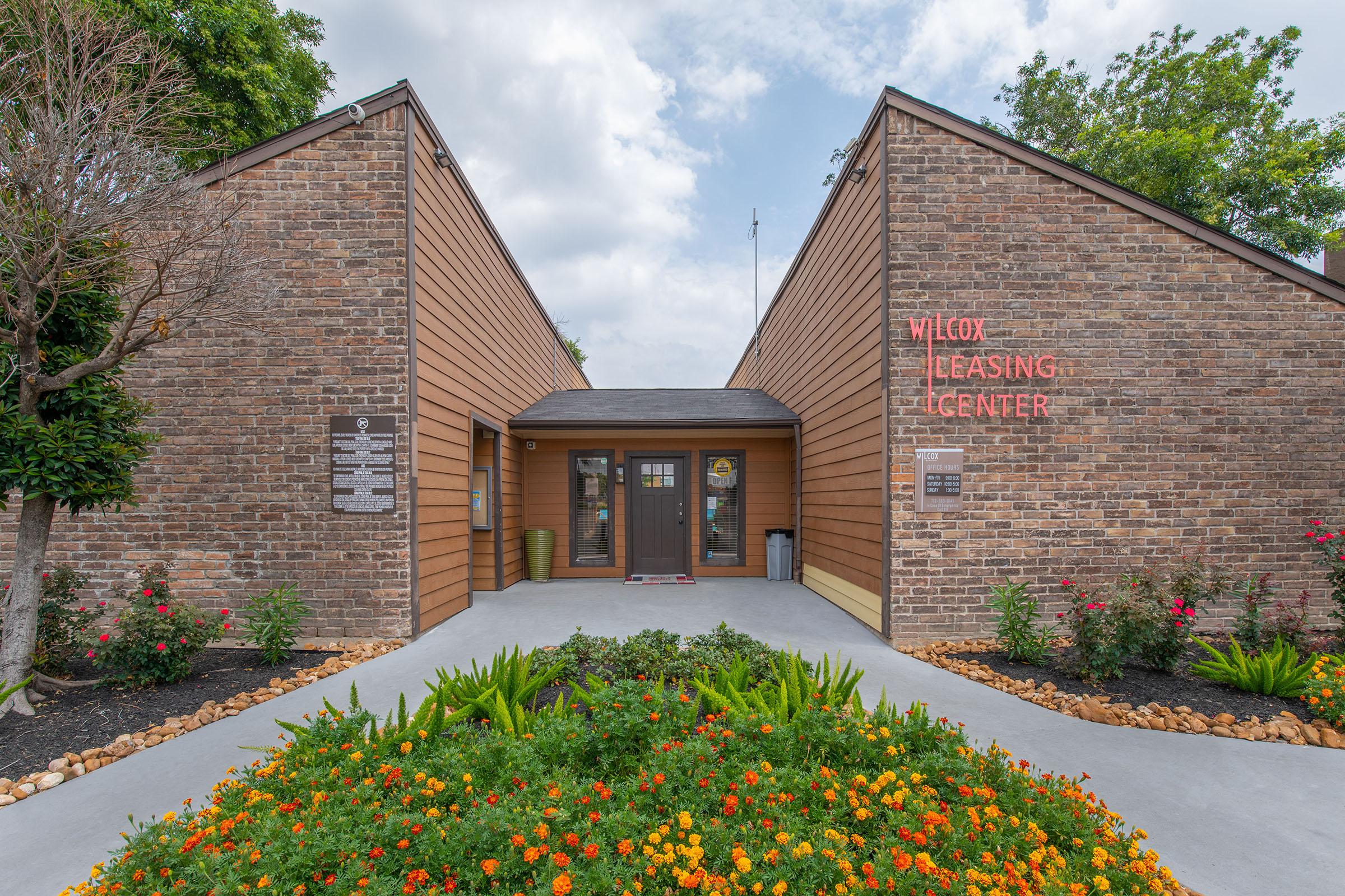 a close up of a flower garden in front of a brick building