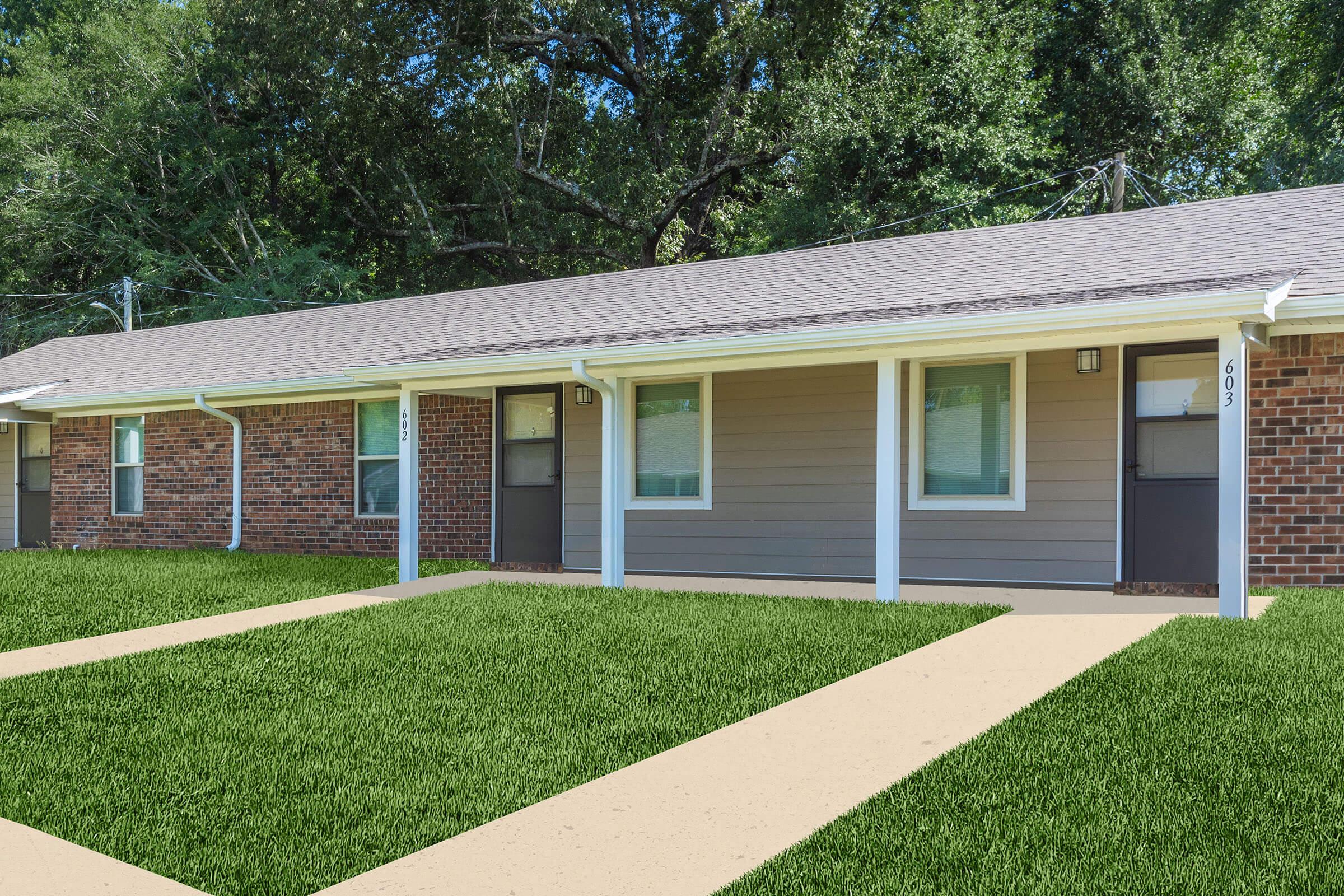 a house with a lawn in front of a brick building