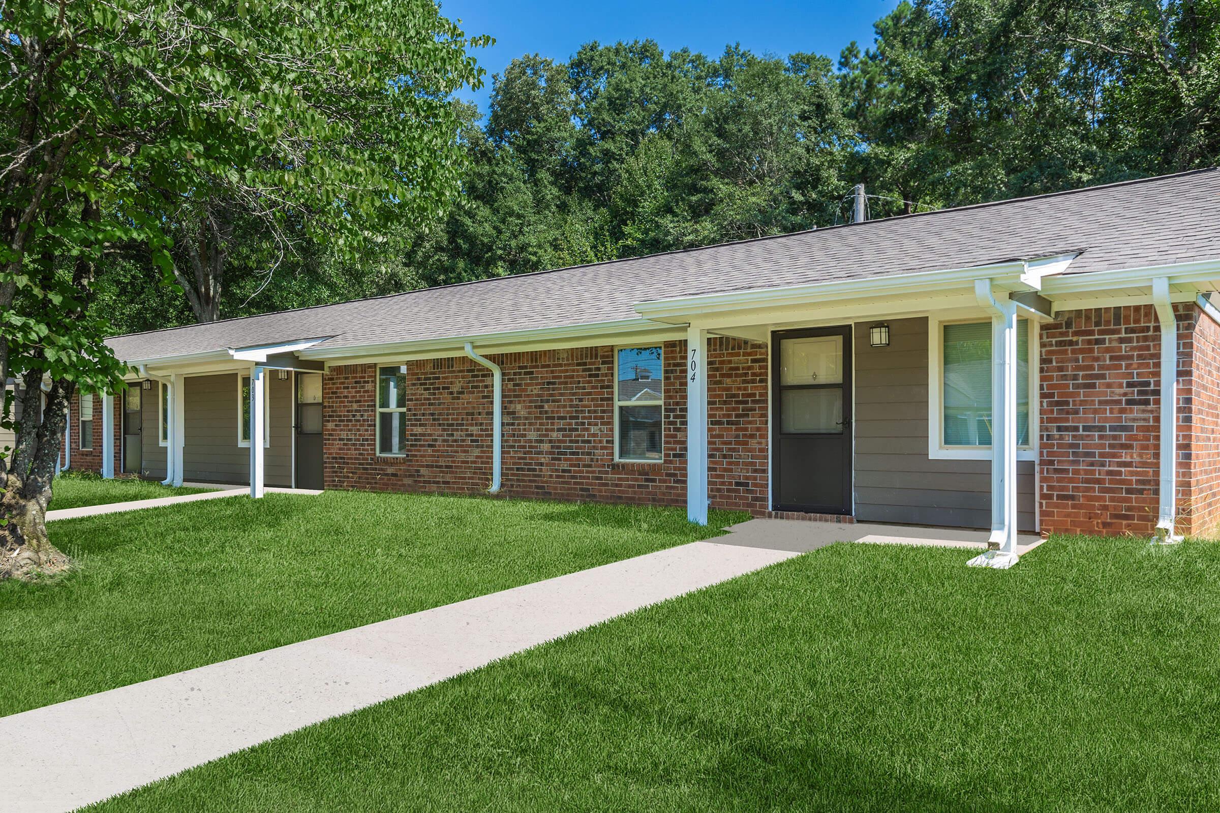 a house with a lawn in front of a brick building