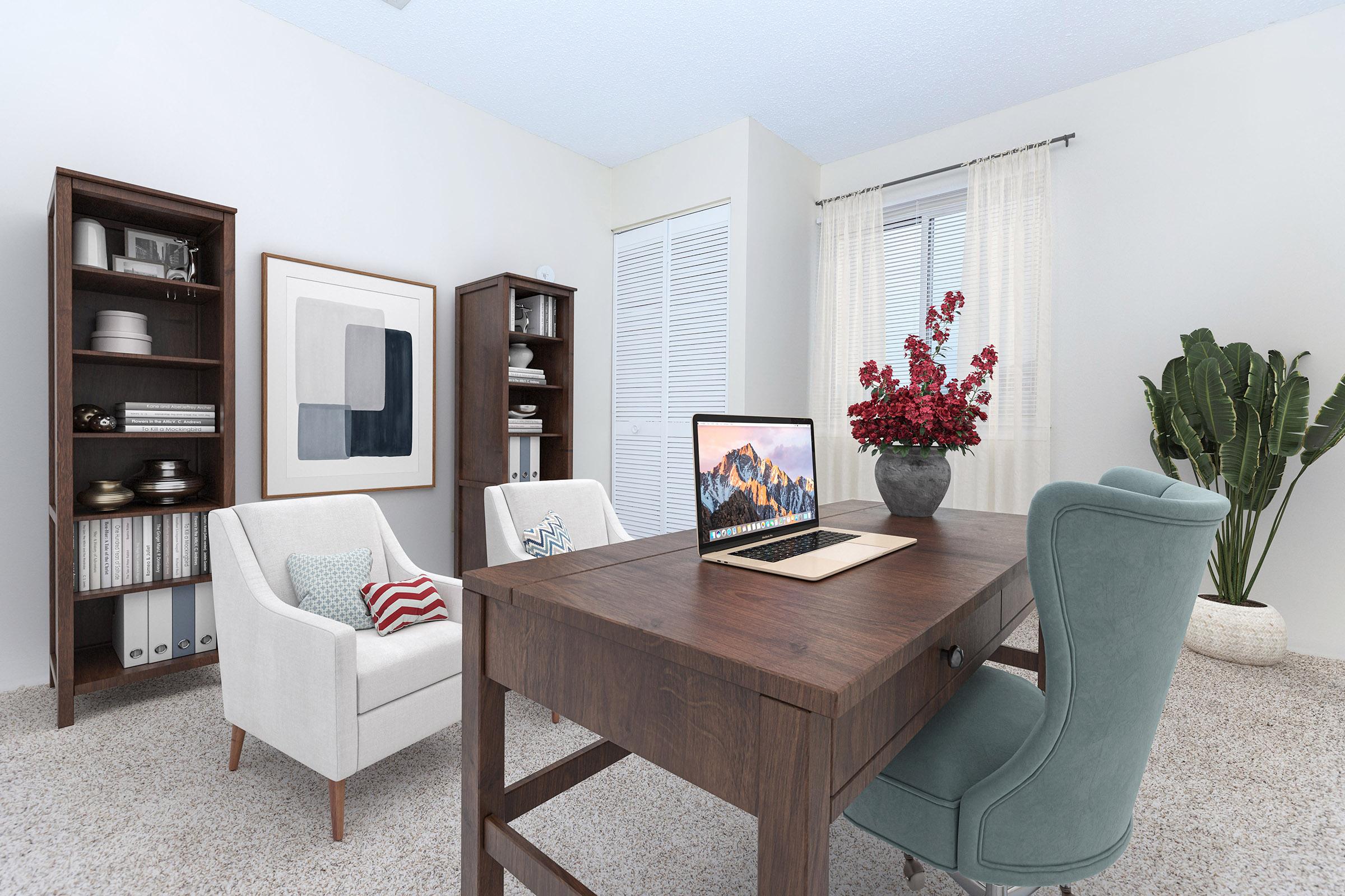 A cozy home office featuring a wooden desk with a laptop, surrounded by two armchairs, a bookshelf, and a potted plant. Natural light pours in through a window with sheer curtains, and a decorative vase with red flowers adds a pop of color to the serene atmosphere.