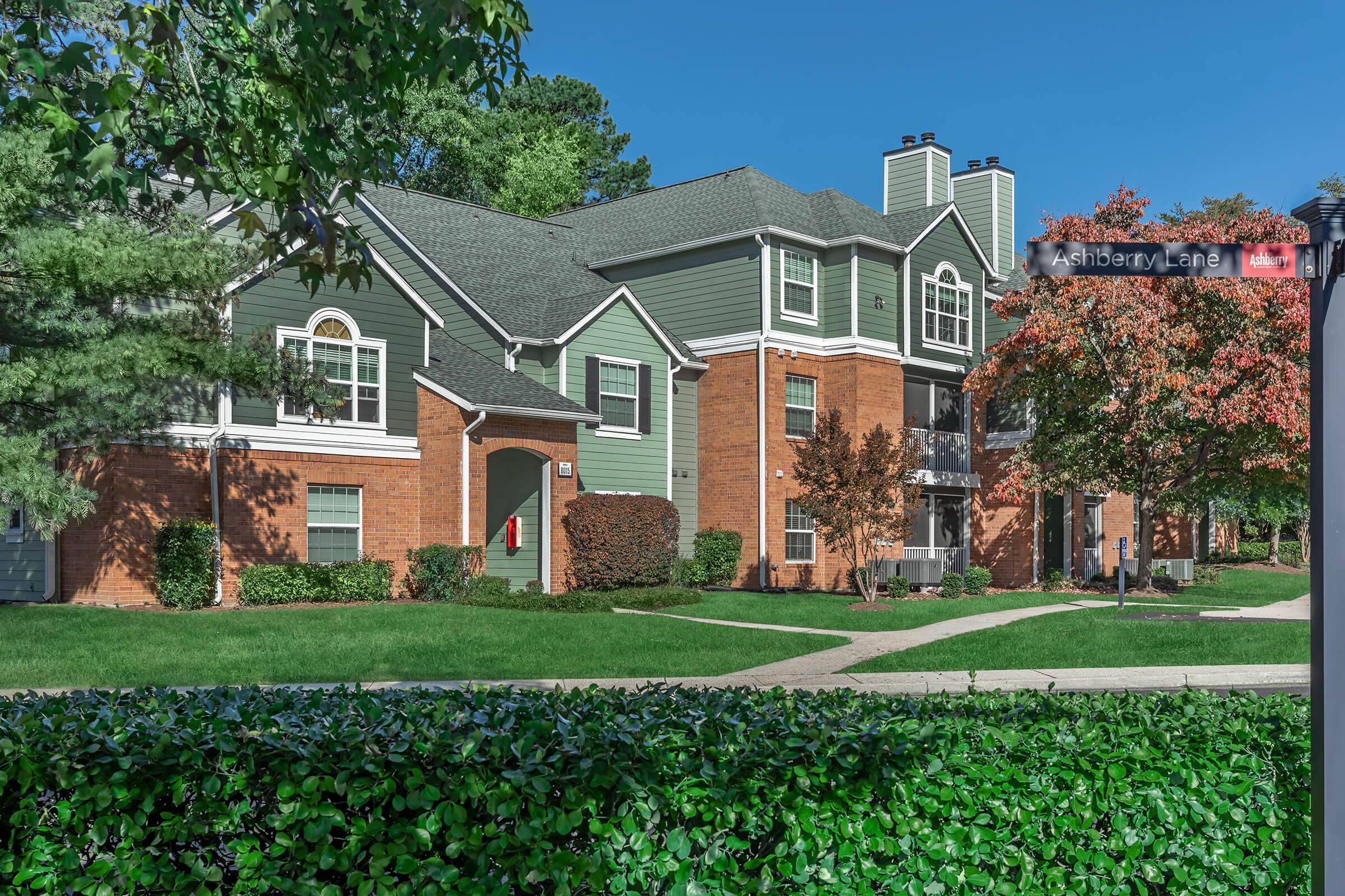 a large brick building with green grass in front of a house