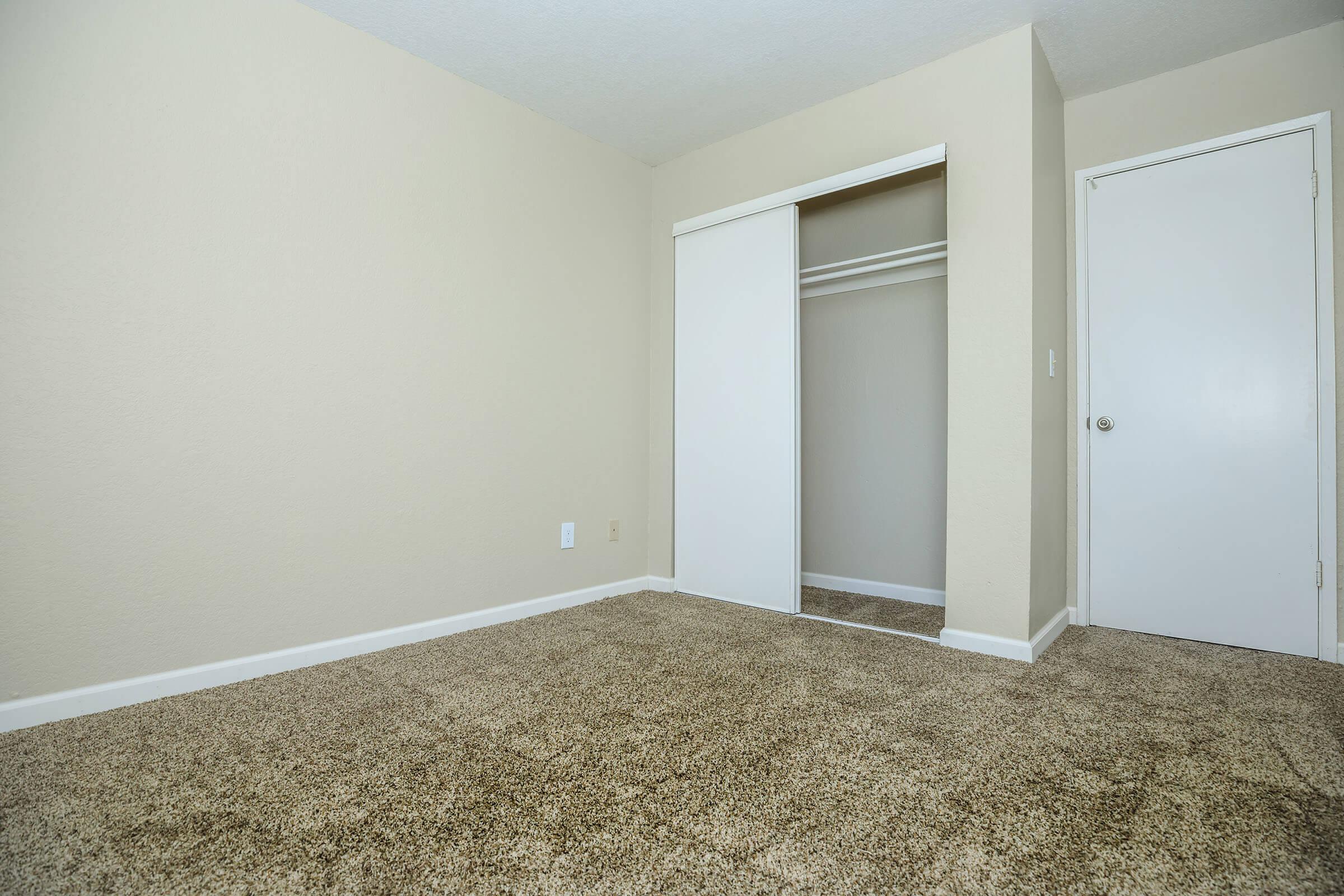 Vacant carpeted bedroom with open sliding closet doors