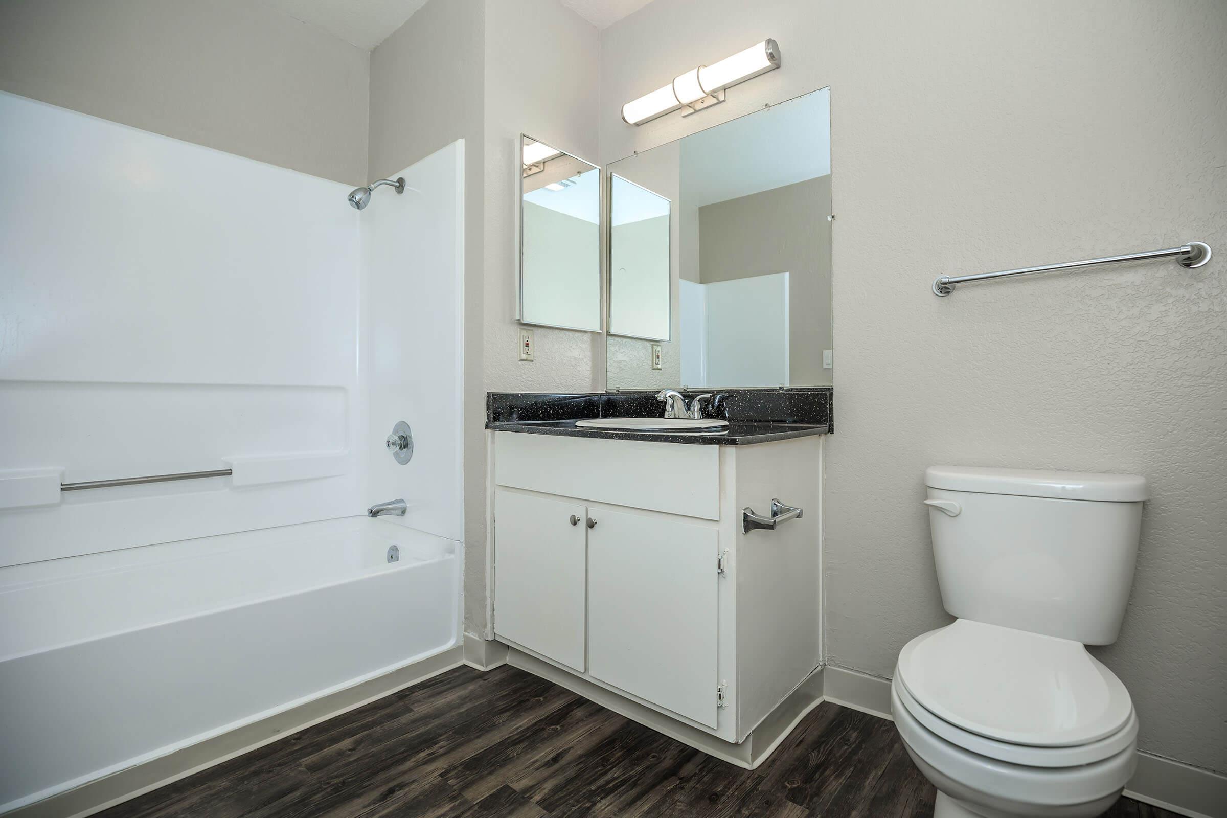 Bathroom with wooden floors and white cabinets