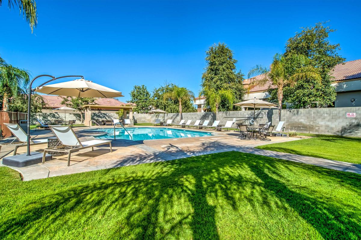 Community pool with green grass and yellow umbrellas