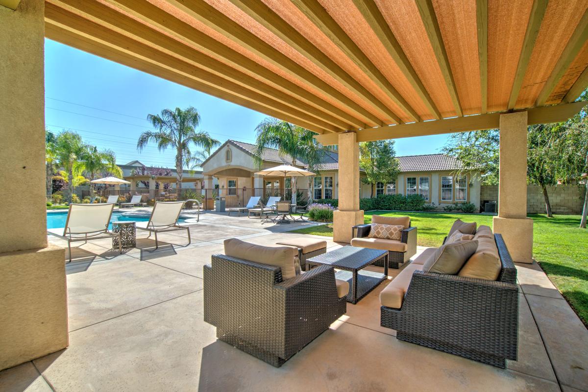 Tan couches and chairs under a pergola