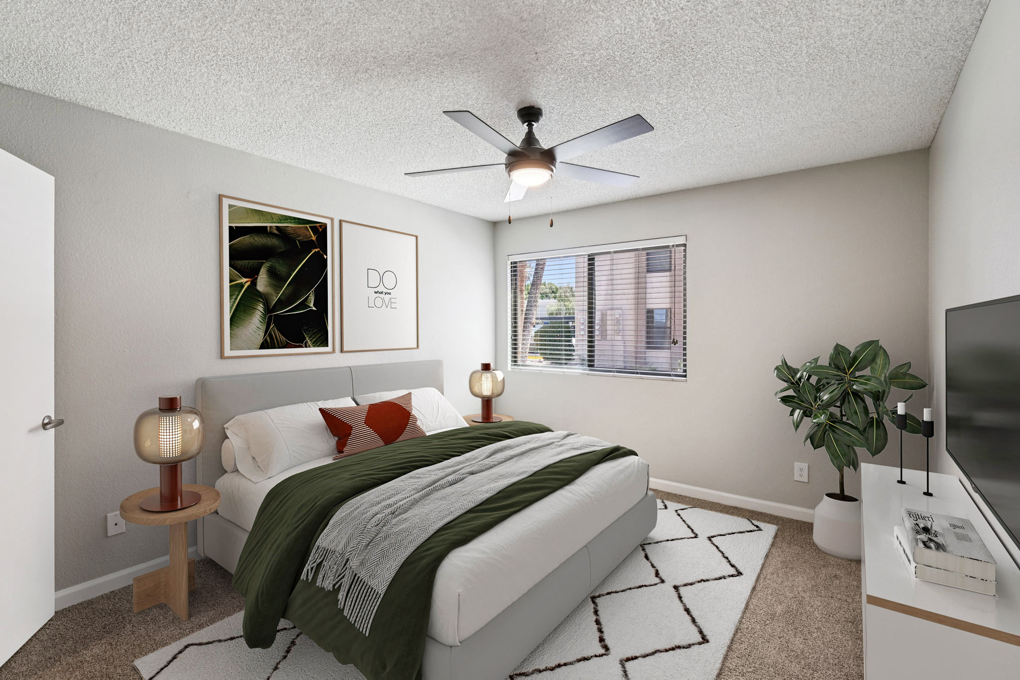 A cozy bedroom featuring a queen-sized bed with green and white bedding, two stylish bedside lamps, and framed leaf artwork on the wall. There's a potted plant in the corner, a large window with blinds allowing natural light, and a TV on a white media console. Soft textures and a modern design create a welcoming atmosphere.