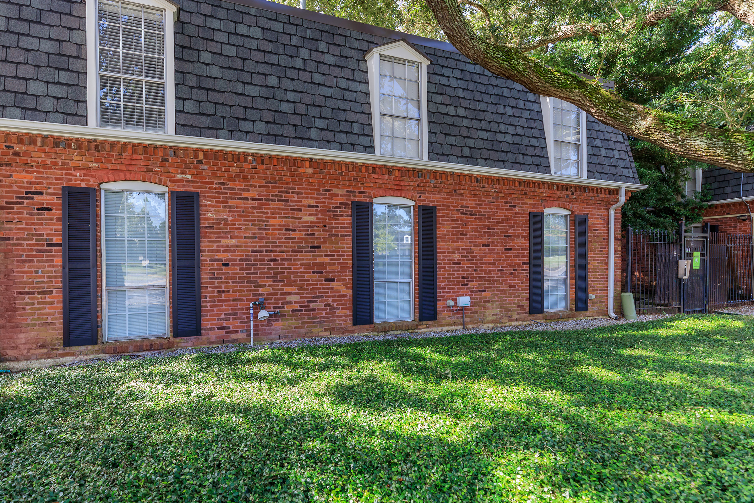 a large brick building with grass in front of a house