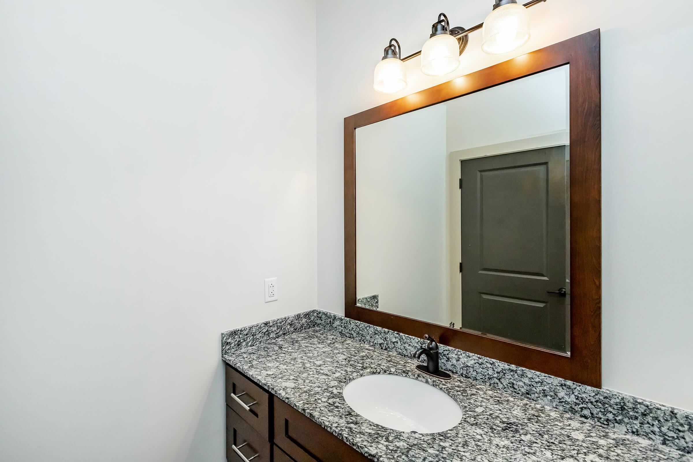 Bathroom 2 with single sink in granite countertop, mirror and lights