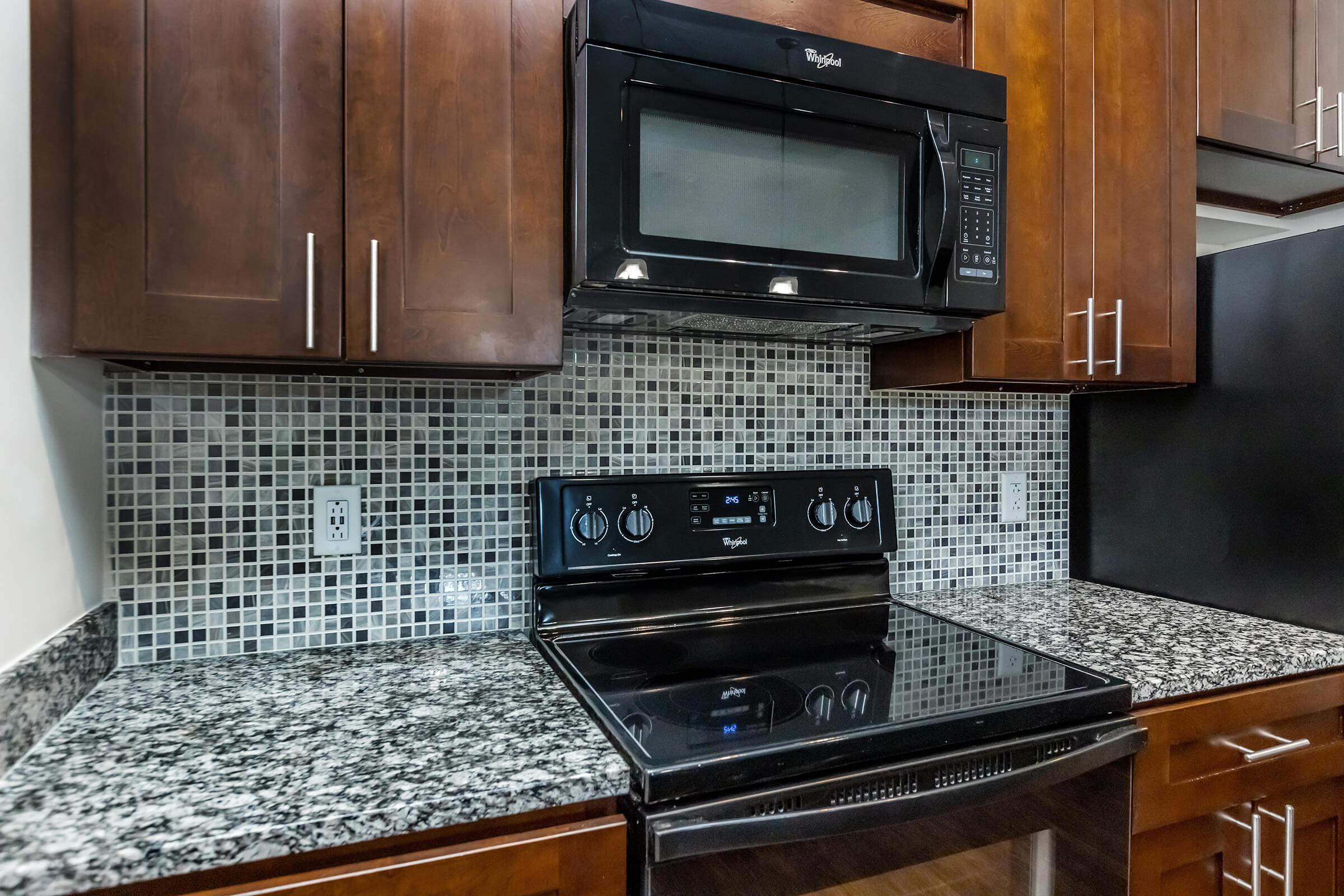 Glass top Stove and Microwave with tile backsplash and granite counters