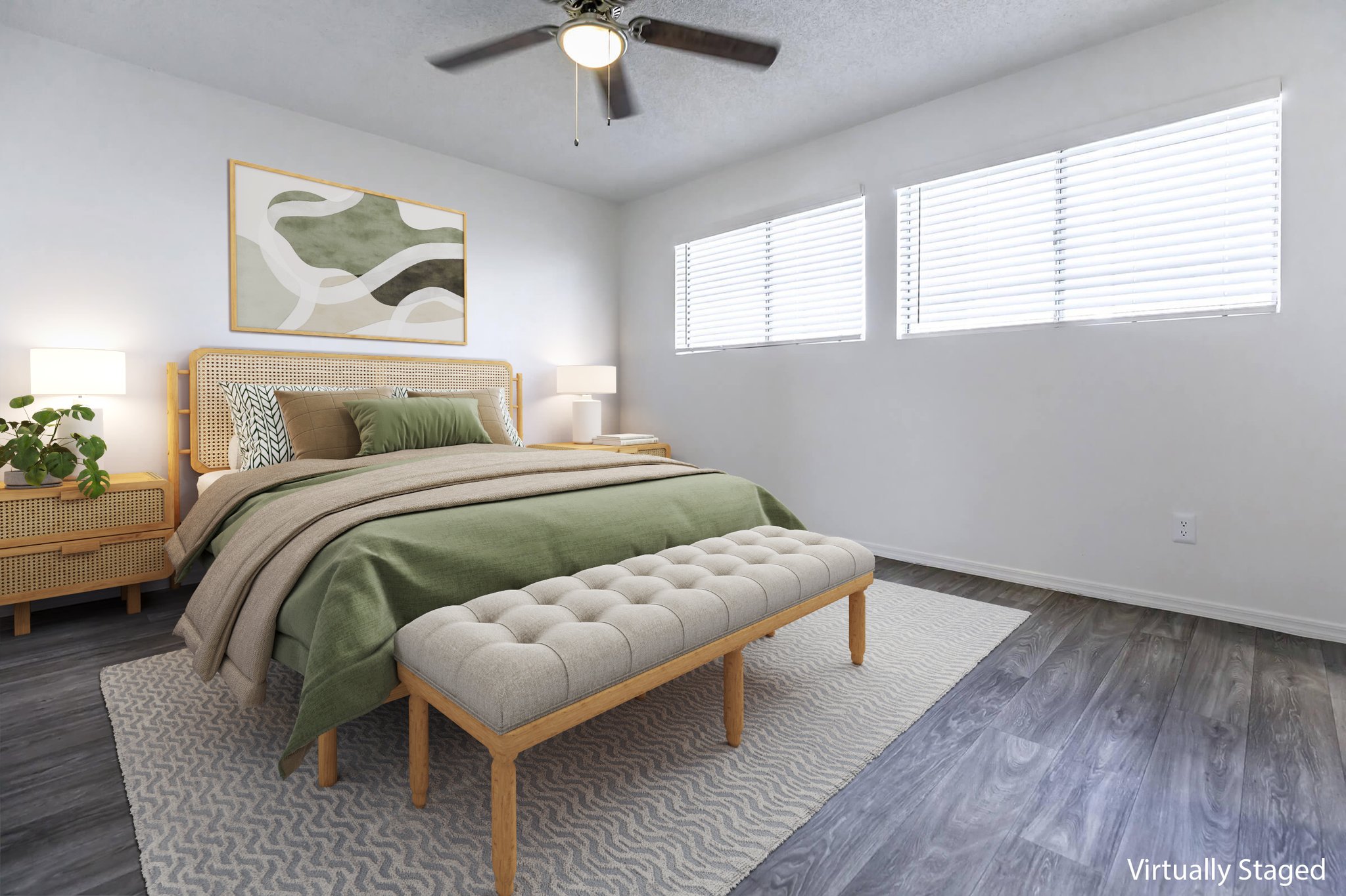 A well-decorated bedroom featuring a bed with green and beige bedding, a tufted bench at the foot, and two bedside lamps on woven side tables. Light streams in through white blinds on the windows, and a modern abstract painting is displayed on the wall above the bed. The floor is a warm-toned wood.